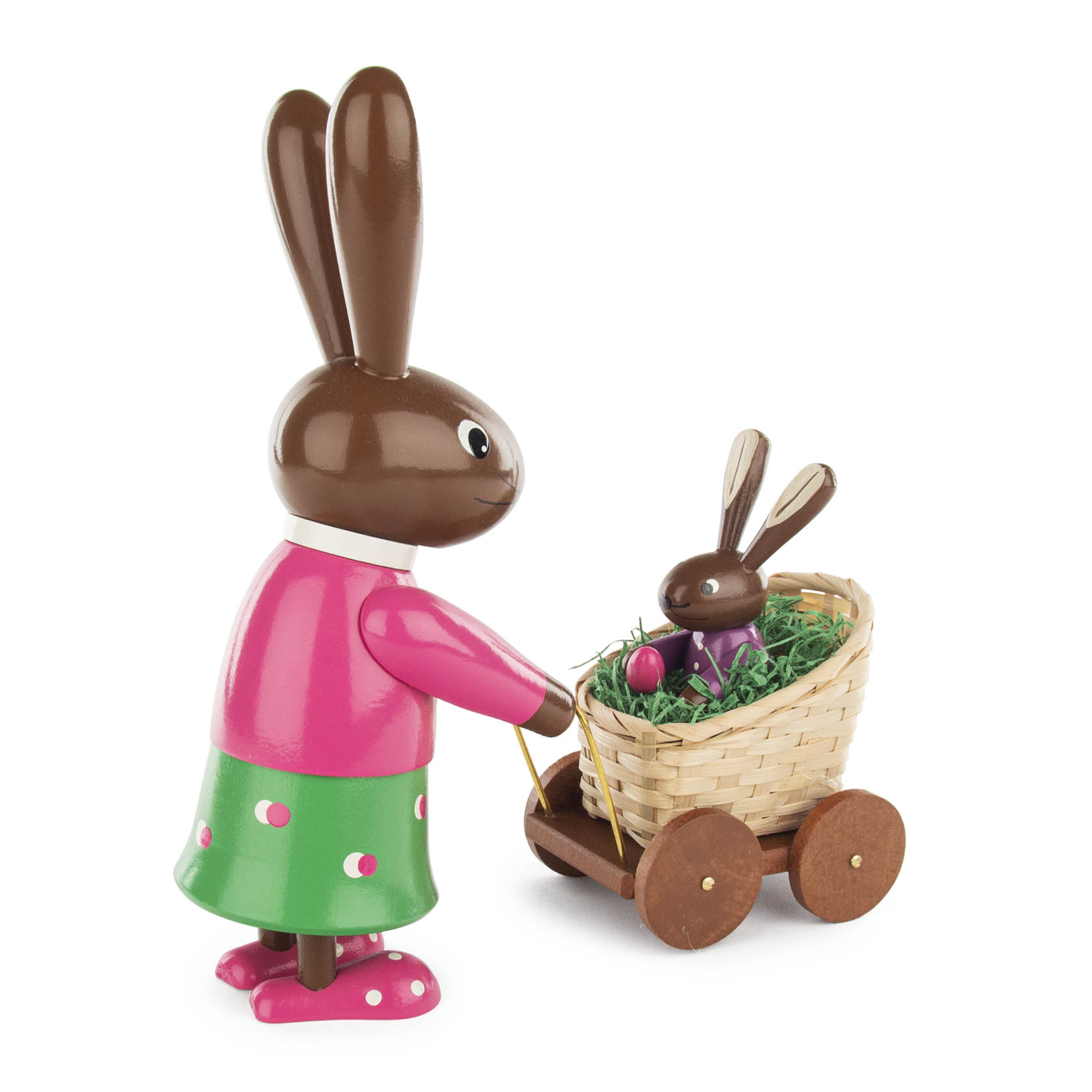 Eine farbenfrohe Häsin-Figur aus Holz schiebt einen Kinderwagen mit einem kleinen Häschen darin. Das Häschen sitzt auf grünem Gras und hält ein rotes Ei.