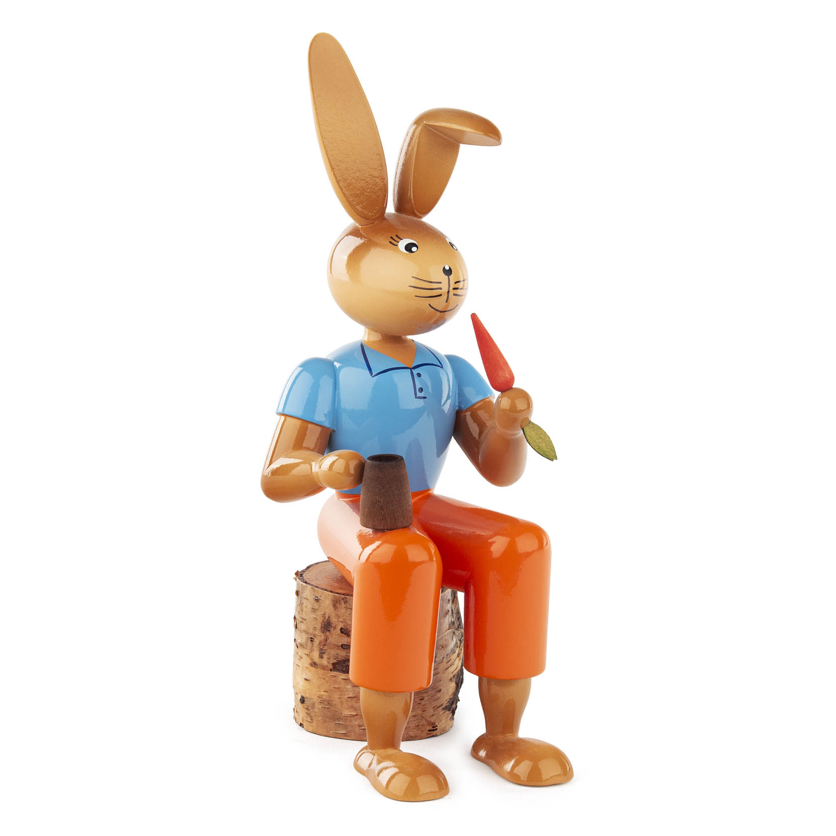 Holzfigur eines sitzenden Hasen mit blauer Jacke und orangefarbener Hose, hält eine Möhre und eine Tüte in den Händen. im Dregeno Online Shop günstig kaufen