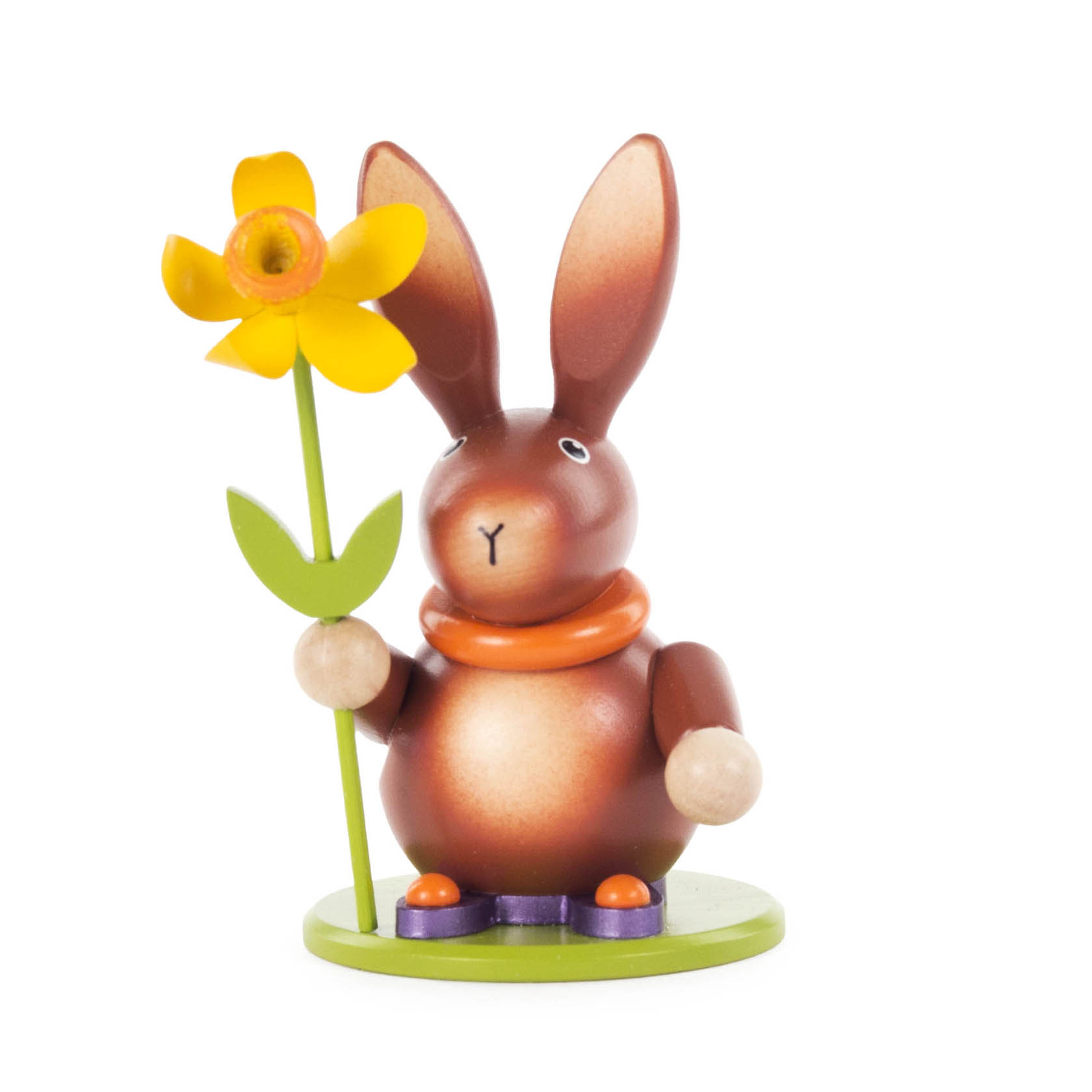 Ein hölzerner, brauner Hase mit großen Ohren hält eine gelbe Narzisse. Der Hase trägt eine orangefarbene Halskrause und steht auf einem grünen Sockel. im Dregeno Online Shop günstig kaufen