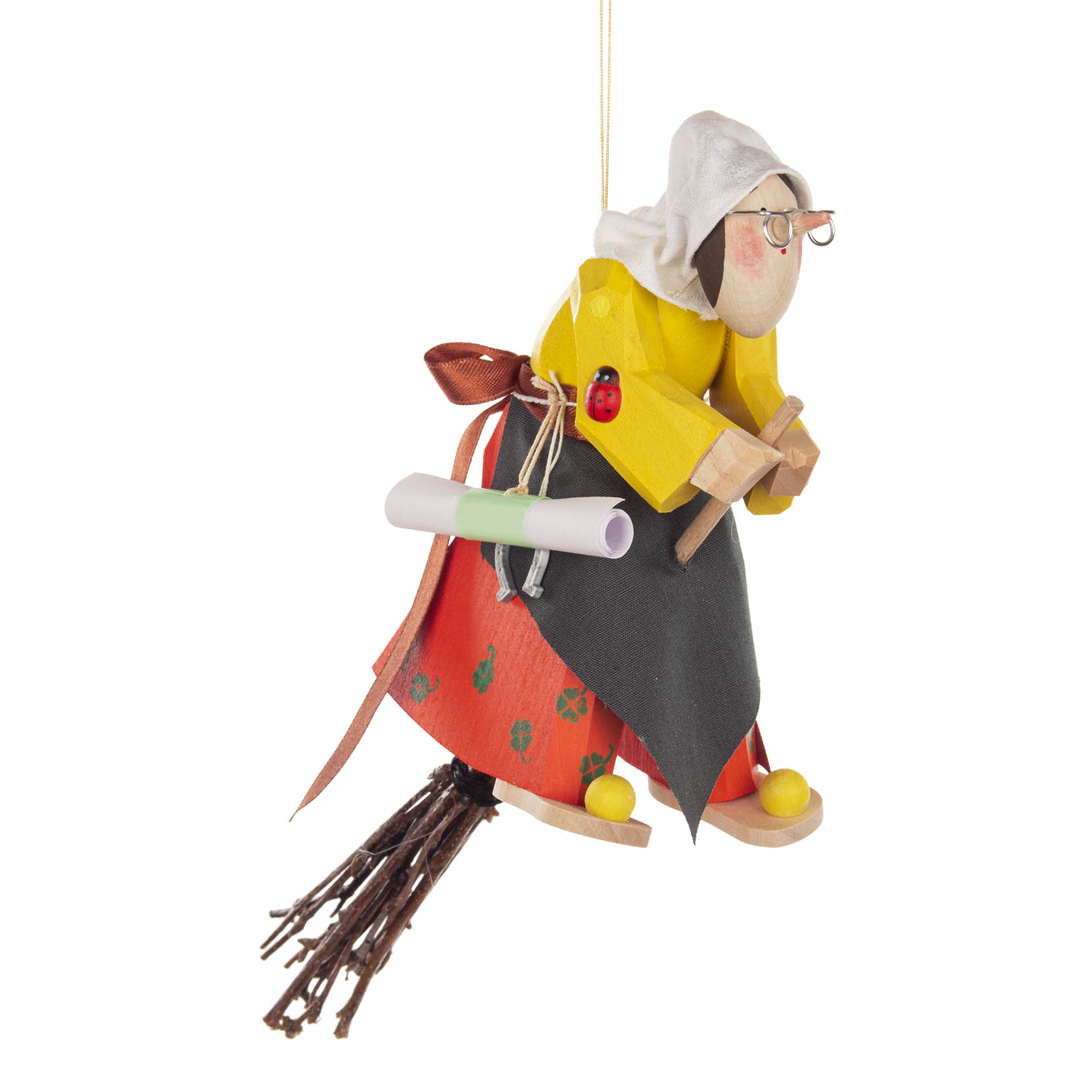 Holzfigur einer Hexe mit gelbem Hemd, rotem Kleid und schwarzer Schürze, sitzt auf einem Reisigbesen. Sie trägt eine Brille, Kopftuch und hat eine Schriftrolle. im Dregeno Online Shop günstig kaufen