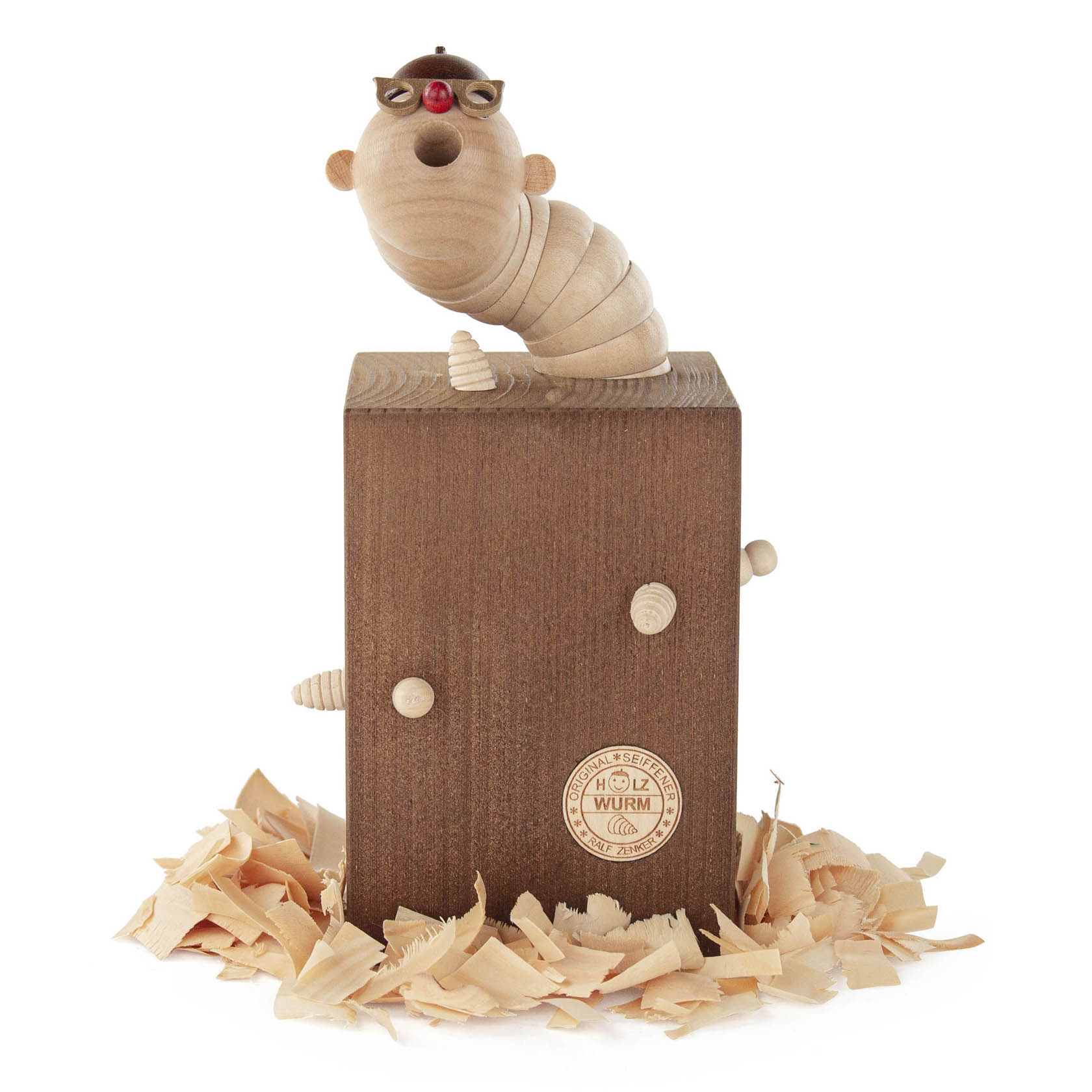 Eine handgefertigte Räucherfigur in Form eines Holzwurms, der auf einem Holzstück sitzt. Mit einer Pfeife im Mund und Holzspänen um ihn herum. im Dregeno Online Shop günstig kaufen