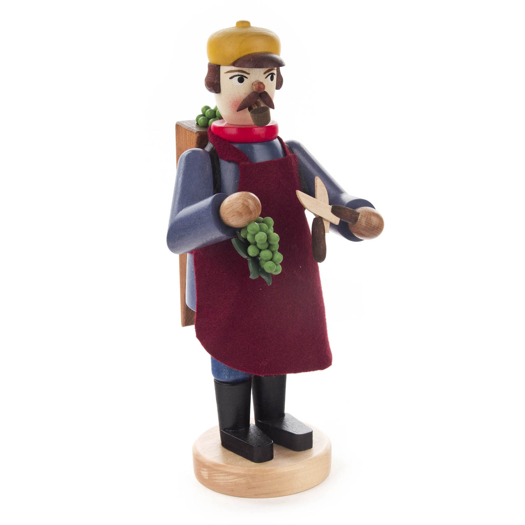 Holzfigur eines Winzers mit gelber Mütze, roter Schürze und einer Traube in der Hand. Er hält eine Schere und hat einen Rucksack.