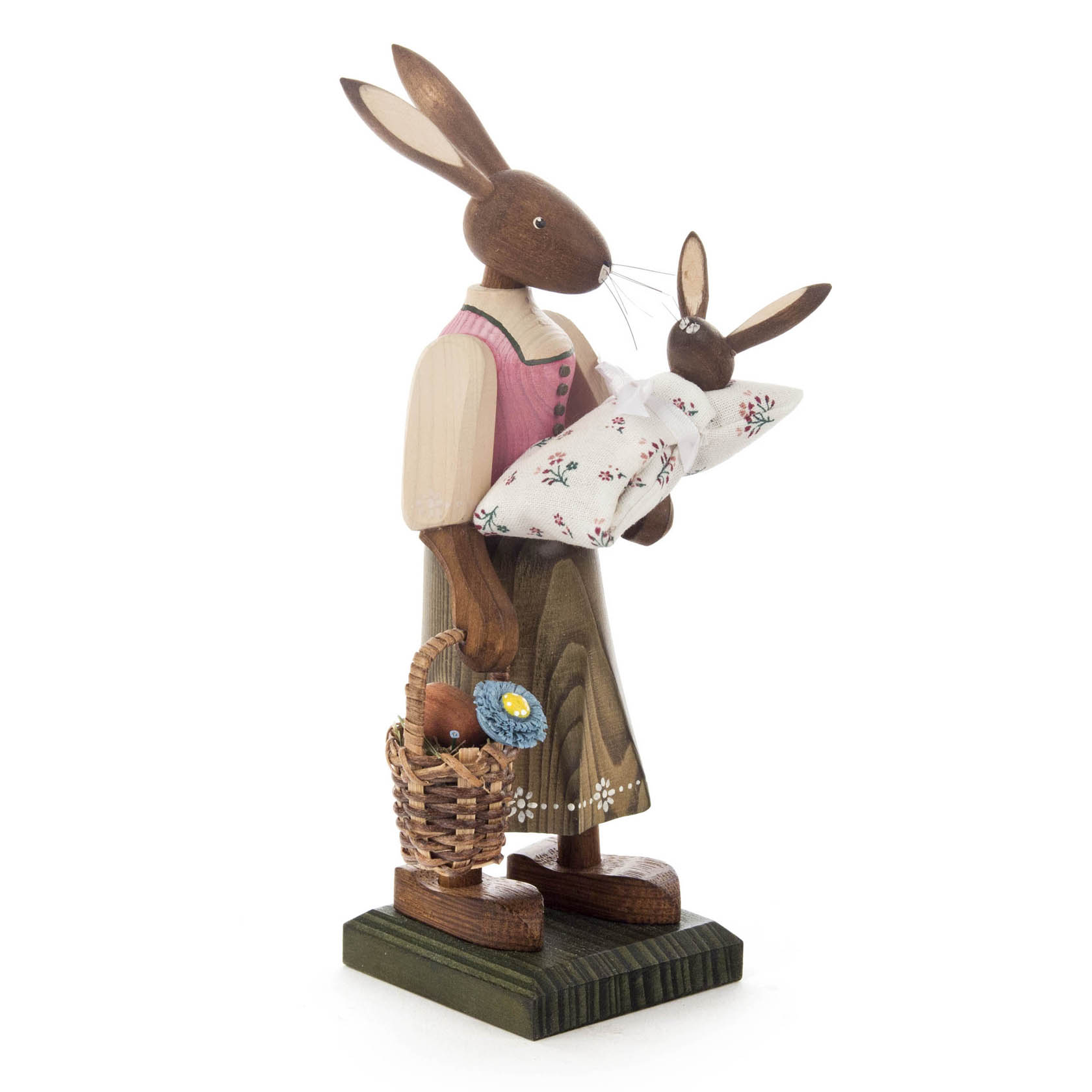 Tall female hare figure in a pink dress holding a baby hare in a floral blanket, with a basket of flowers on a wooden base.