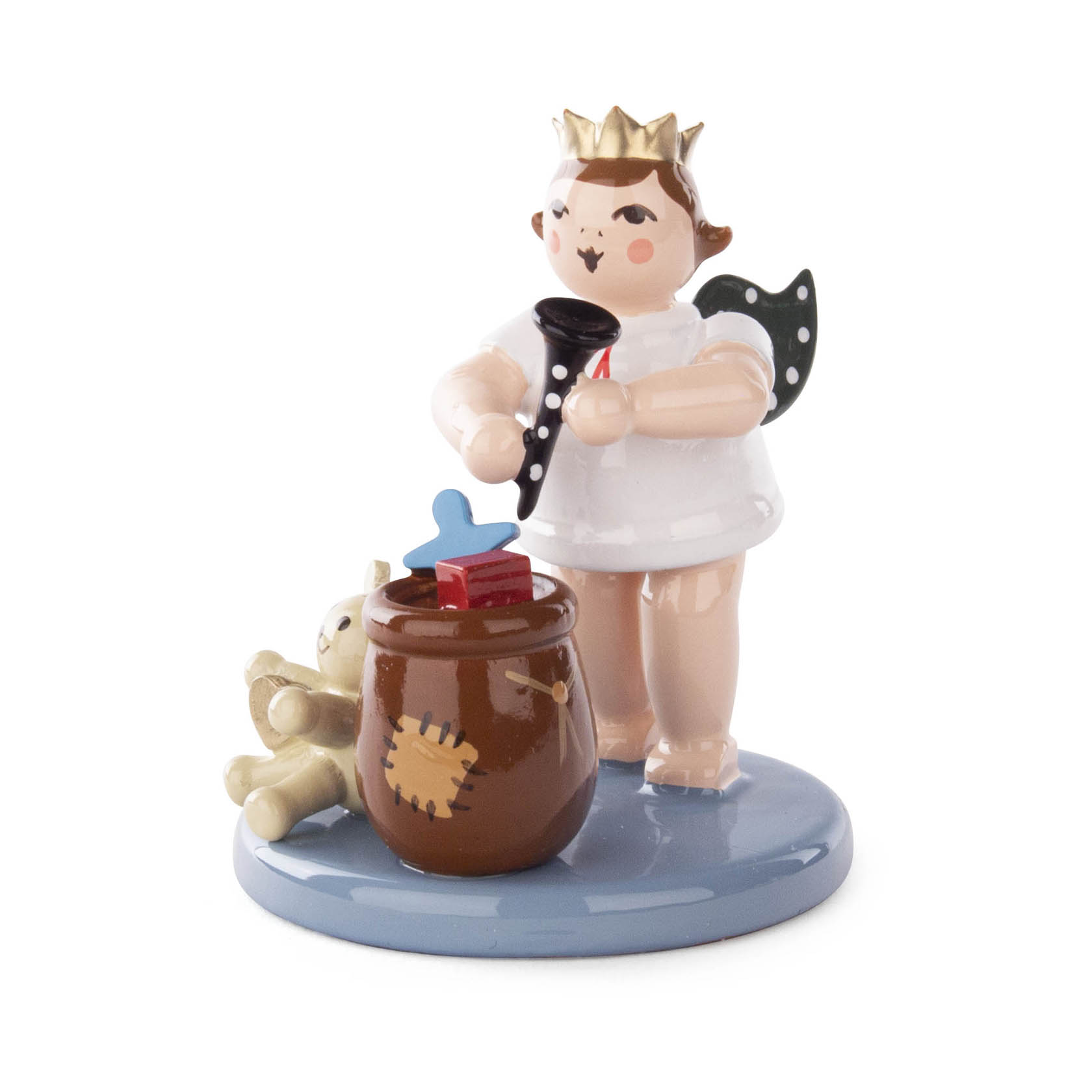 Figur eines Weihnachtsengels mit Krone, der eine Trompete spielt. Neben ihm ein Sack mit Geschenken und ein kleiner Bär. im Dregeno Online Shop günstig kaufen