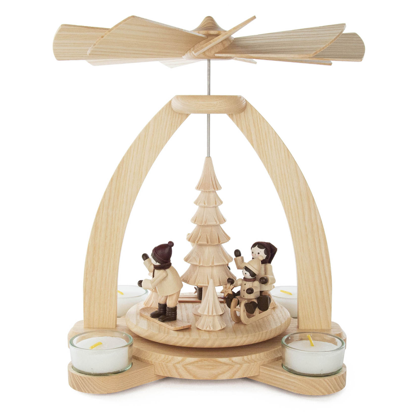 Holz-Windlichtpyramide mit Wintersport-Thema, drei holzgeschnitzte Figuren mit Skiern, umgeben von Teelichtern, mittig ein Weihnachtsbaum.