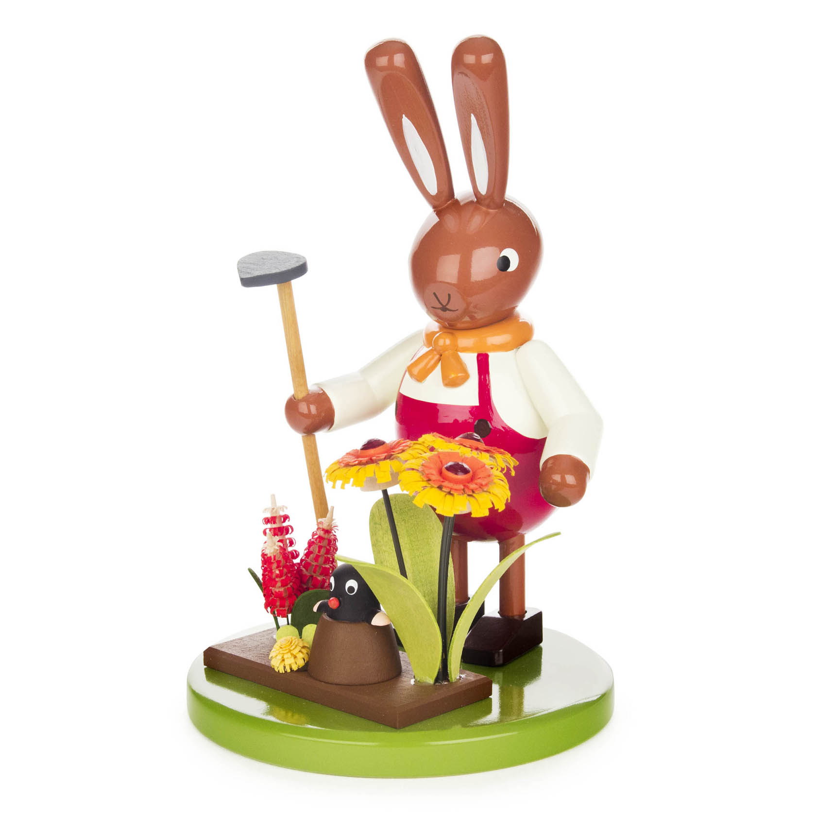 Holzfigur eines Hasen in roter Latzhose hält einen Hammer und schaut auf einen süßen Maulwurf, der inmitten von bunten Blumen aus der Erde guckt.