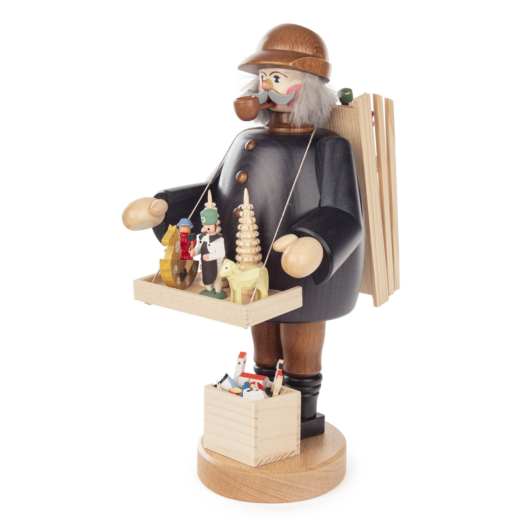 Räuchermann in Form eines Spielzeughändlers mit schwarzem Mantel und braunem Hut, eine Pfeife im Mund. Er trägt eine Kiste mit Miniaturspielzeugfiguren.