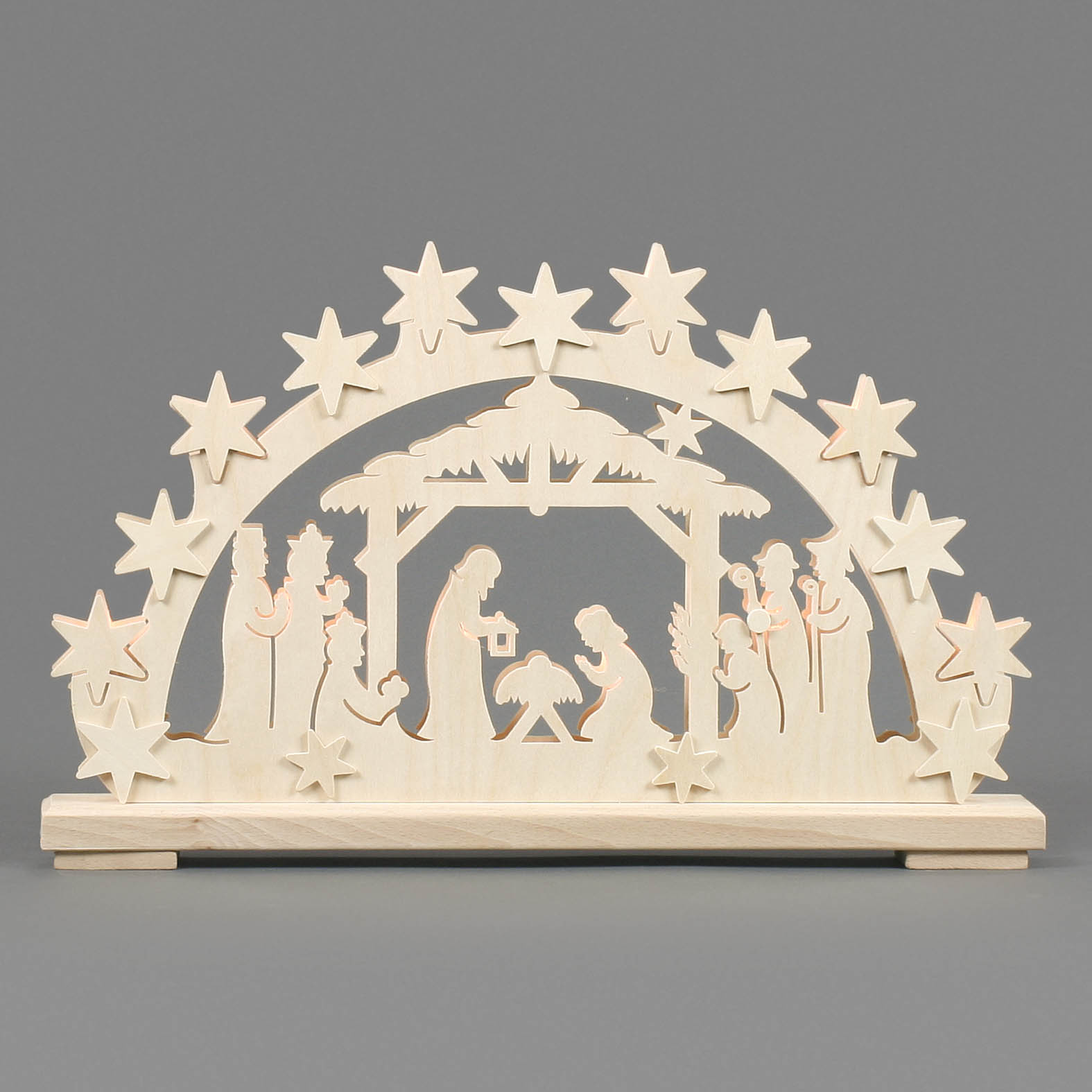 A wooden arch with carved figures of the Nativity scene, including Mary, Joseph, baby Jesus in a manger, shepherds, and angels, illuminated subtly.