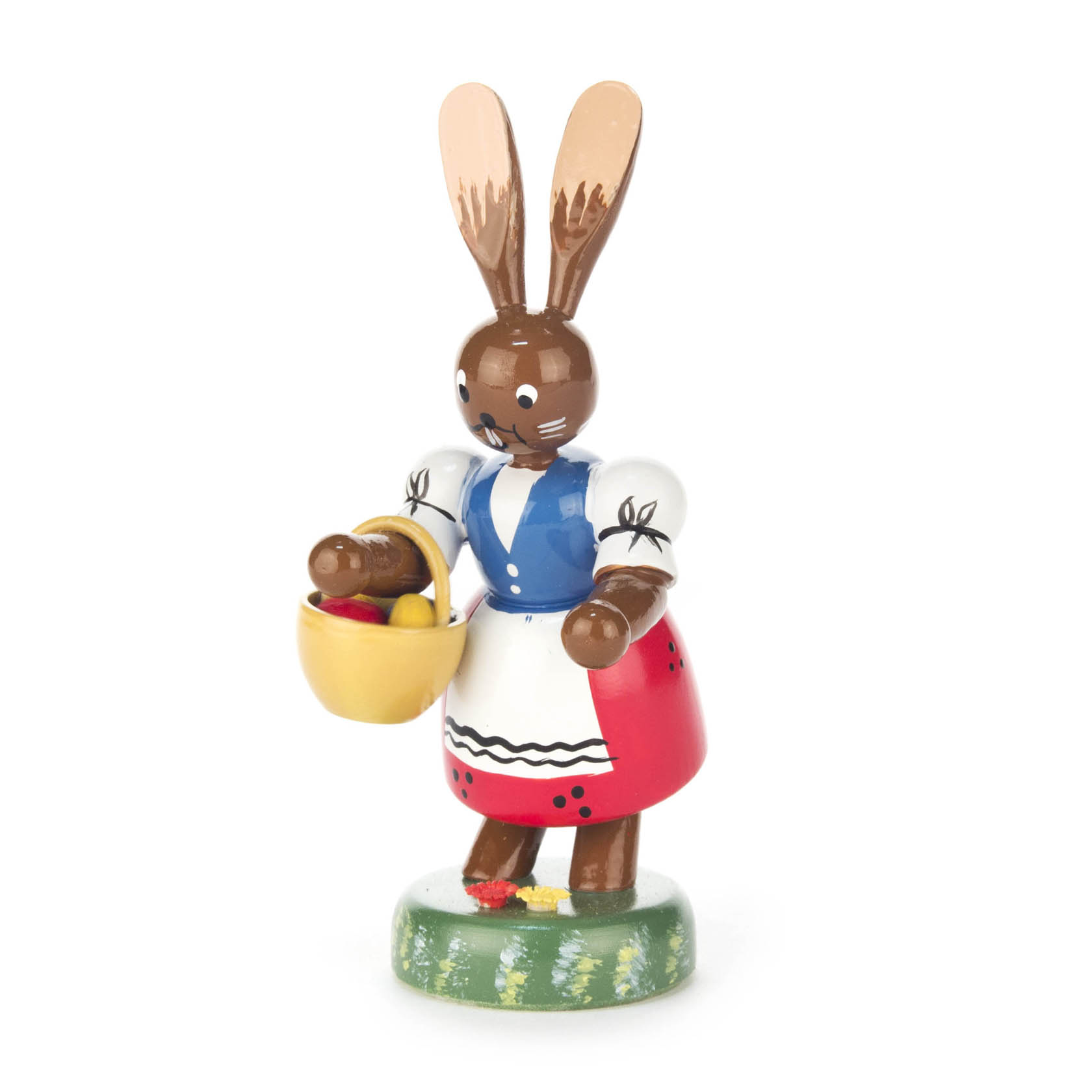 Eine hölzerne Hasenfigur, die traditionelle bunte Kleidung trägt und einen kleinen gelben Korb mit roten und gelben Eiern hält. im Dregeno Online Shop günstig kaufen