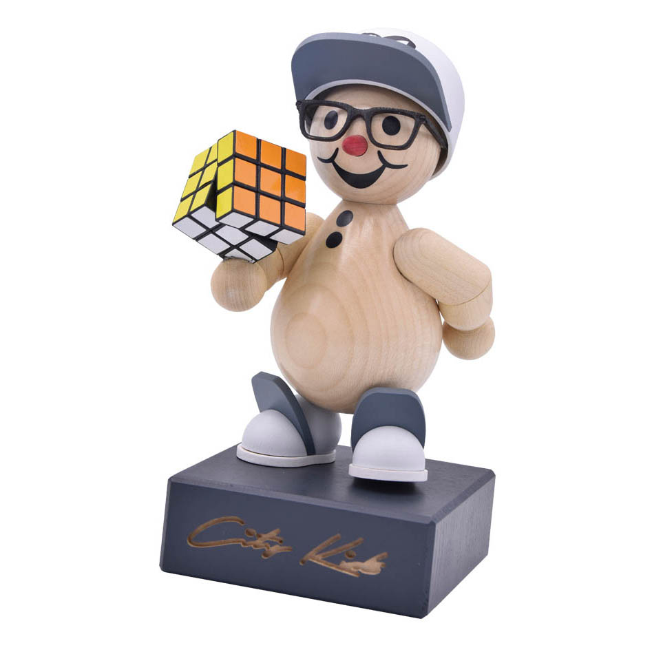 Eine handgefertigte Holzfigur, die einen lächelnden Jungen mit Brille und Mütze darstellt. Er hält einen gelösten Zauberwürfel in der Hand. im Dregeno Online Shop günstig kaufen