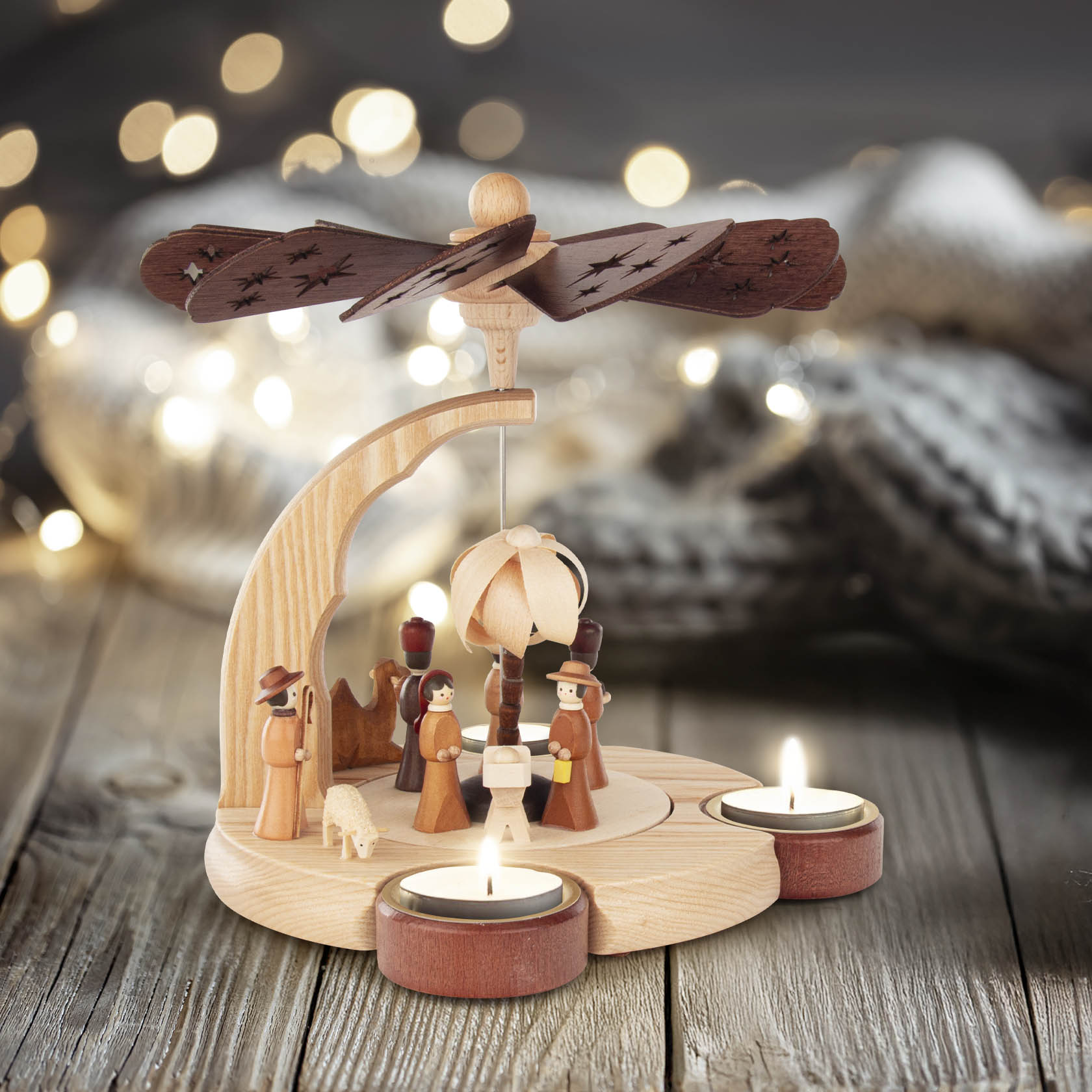 Holzpyramide in Form einer Krippe mit der Darstellung von Jesu Geburt. Figuren aus Holz, zwei Teelichthaltern, sich drehender Propeller oben.