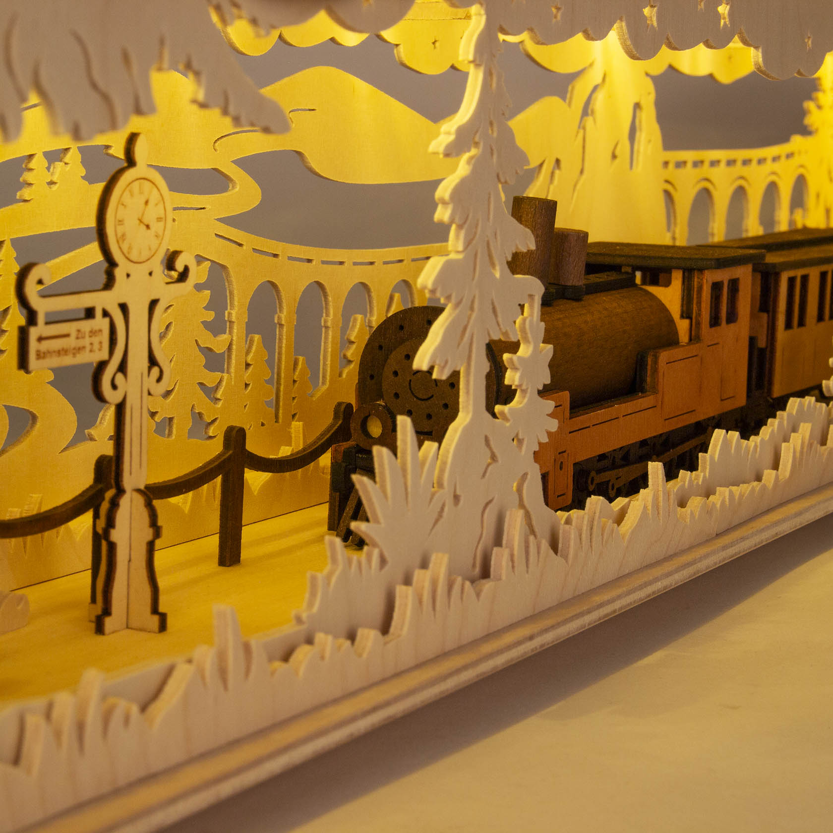 Wooden LED base lamp with a train motif. Features a train engine passing by a station sign in a forest, with viaducts in the background.
