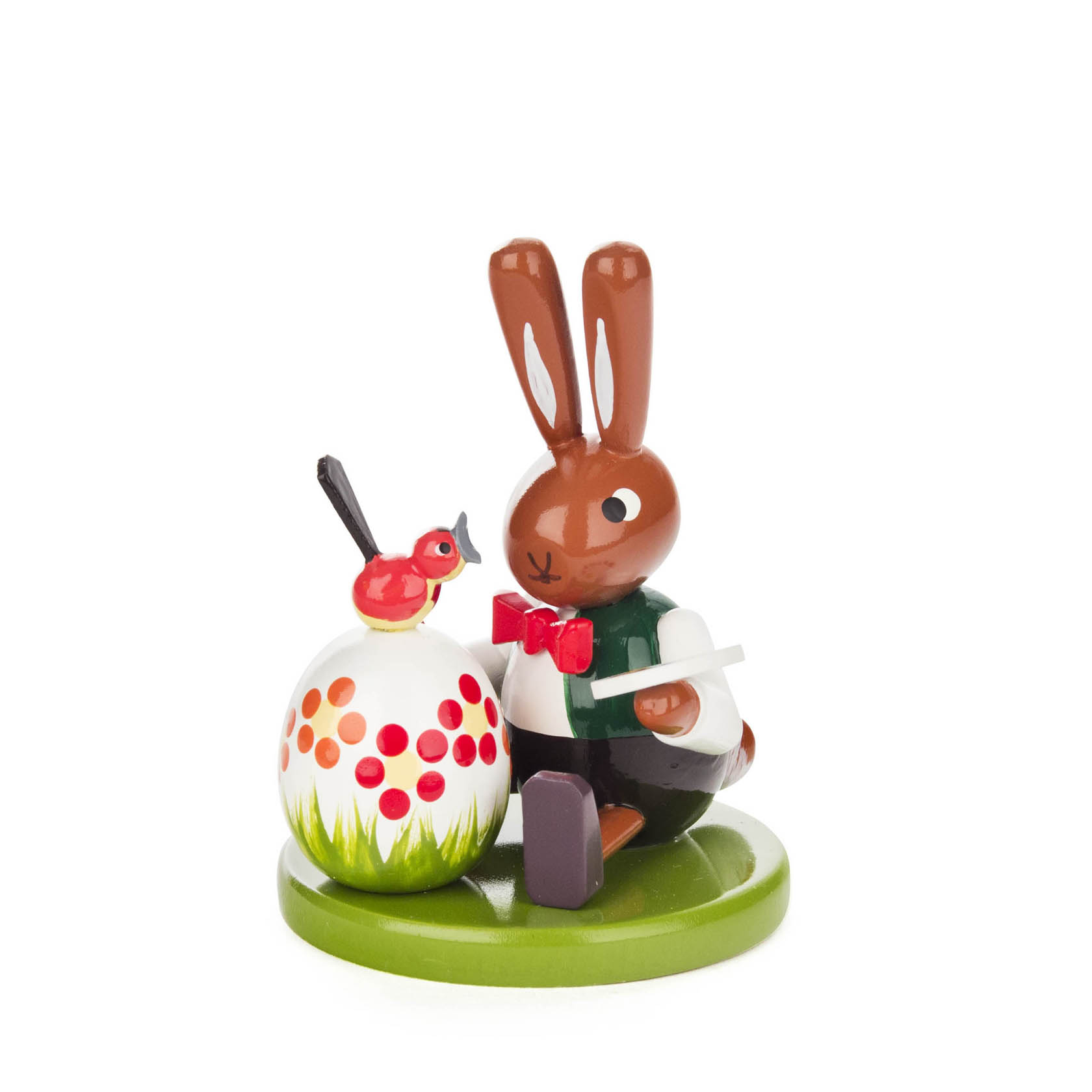 Kleiner Hase mit roter Fliege und grünem Hemd bemalt ein großes Ei mit roten und orangefarbenen Punkten. Ein Vogel sitzt oben auf dem Ei. im Dregeno Online Shop günstig kaufen