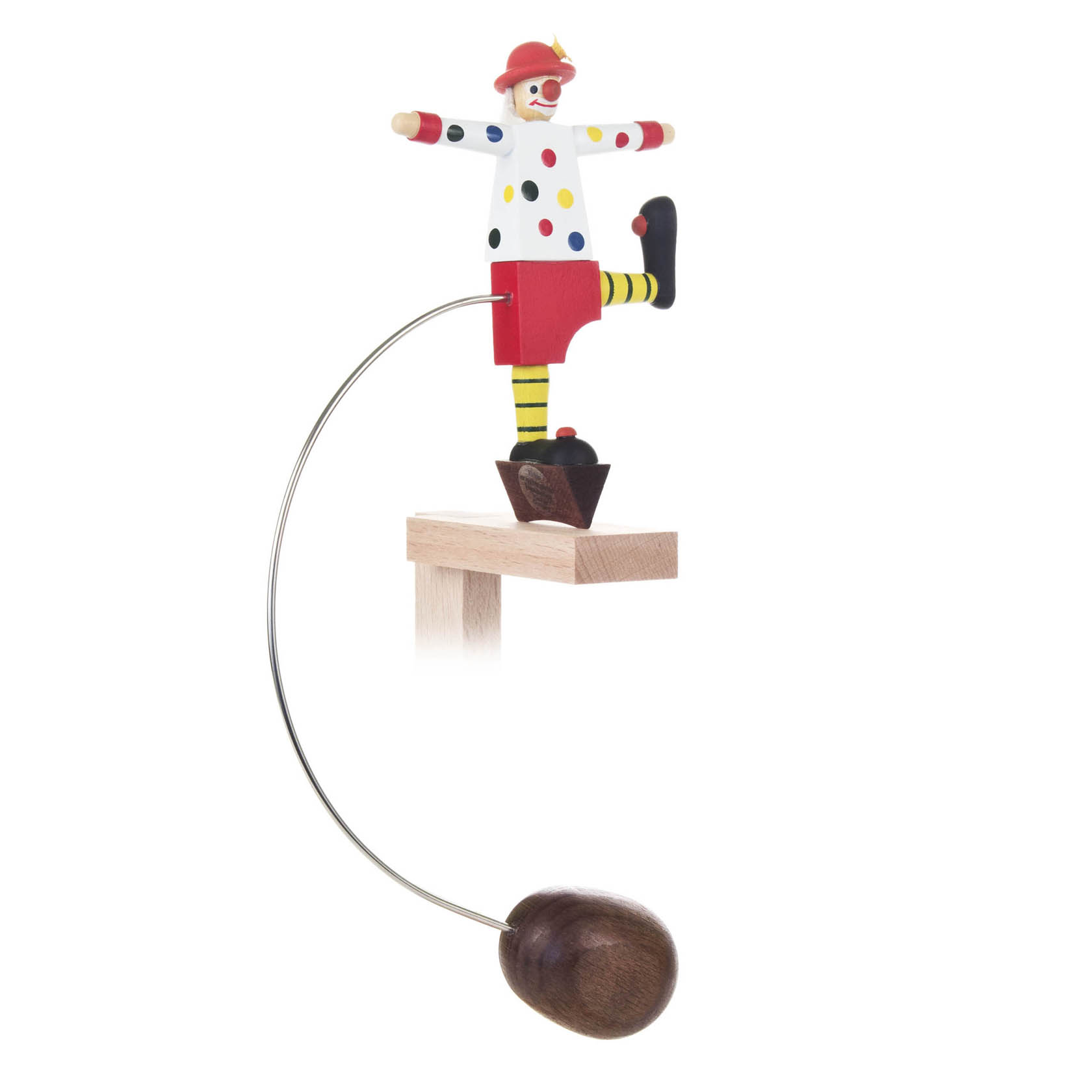 Ein bunter Clown in rot-weißem Outfit mit Punkten steht auf einem gebogenen Metallstab, der an einem hölzernen Sockel befestigt ist. Der Clown hat gelbe Streifen an den Beinen. im Dregeno Online Shop günstig kaufen