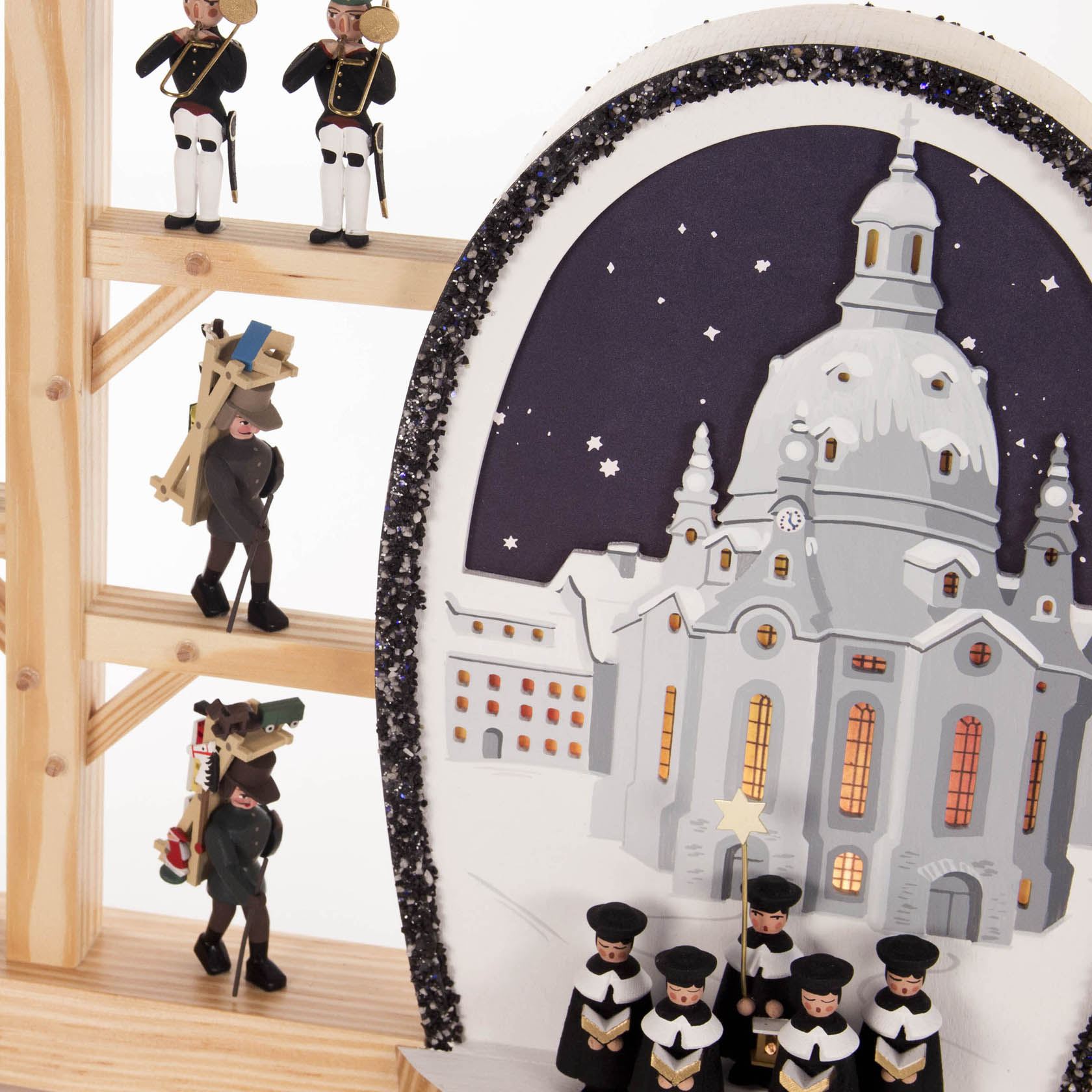 A wooden arch display featuring the illuminated Dresden Frauenkirche, carolers, and festive Erzgebirge figures with electric lights.