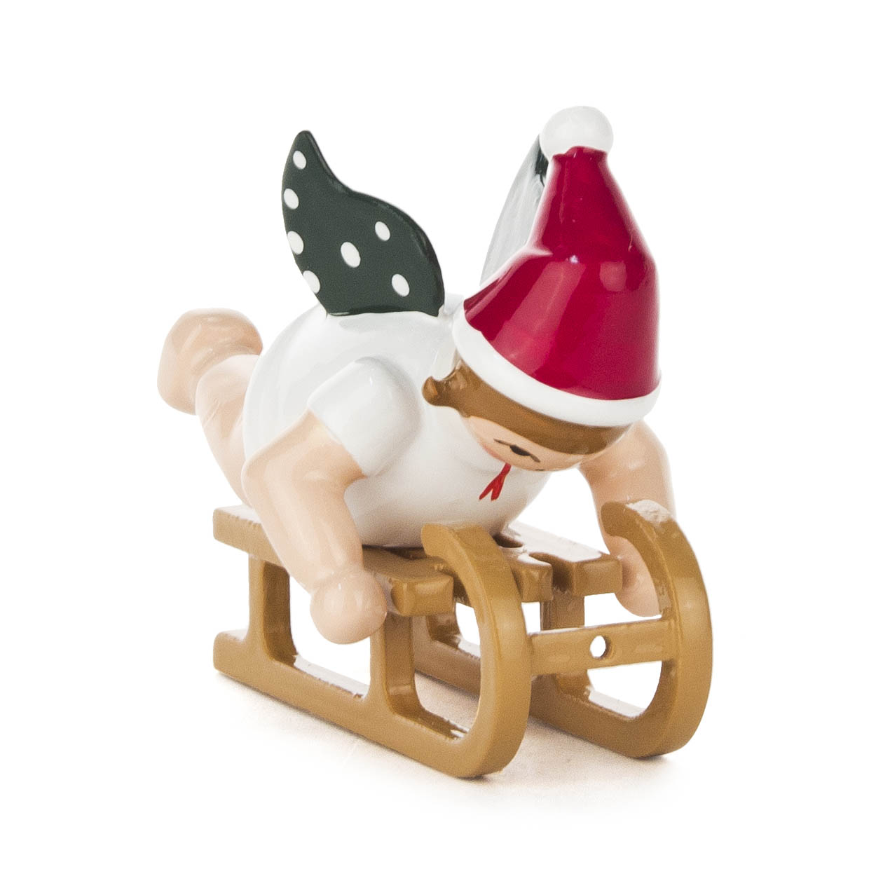 Ein Engel aus Holzfigur, trägt eine rote Weihnachtsmütze und liegt bäuchlings auf einem Holzschlitten. Der Engel hat grüne Flügel mit weißen Punkten. im Dregeno Online Shop günstig kaufen