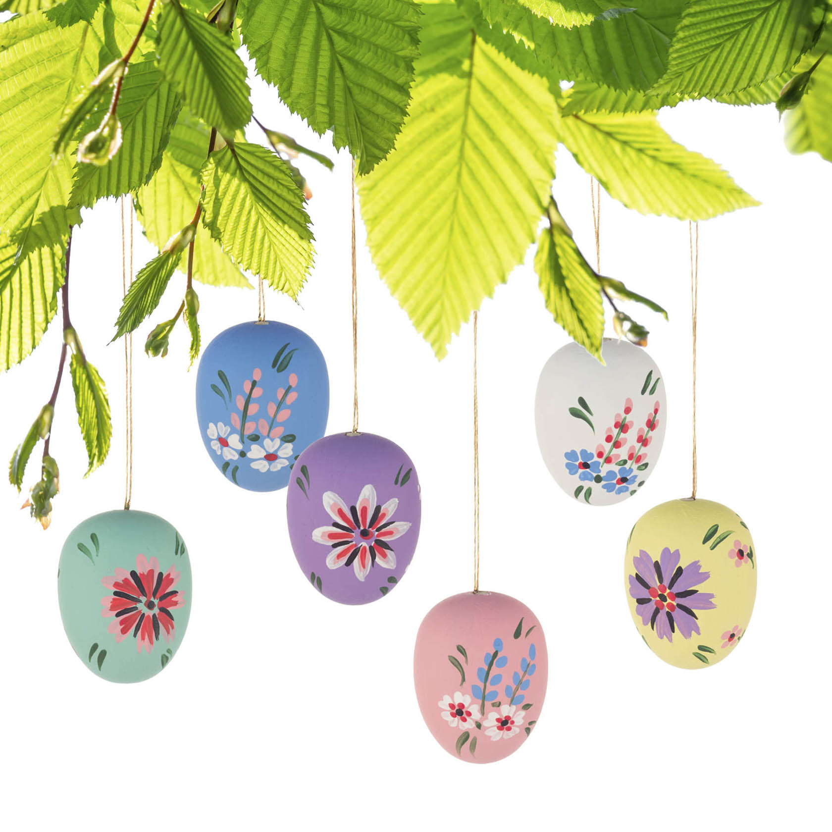 Sechs pastellfarbene Ostereier mit handgemalten Blumenmustern hängen an goldenen Fäden unter grünen Zweigen.