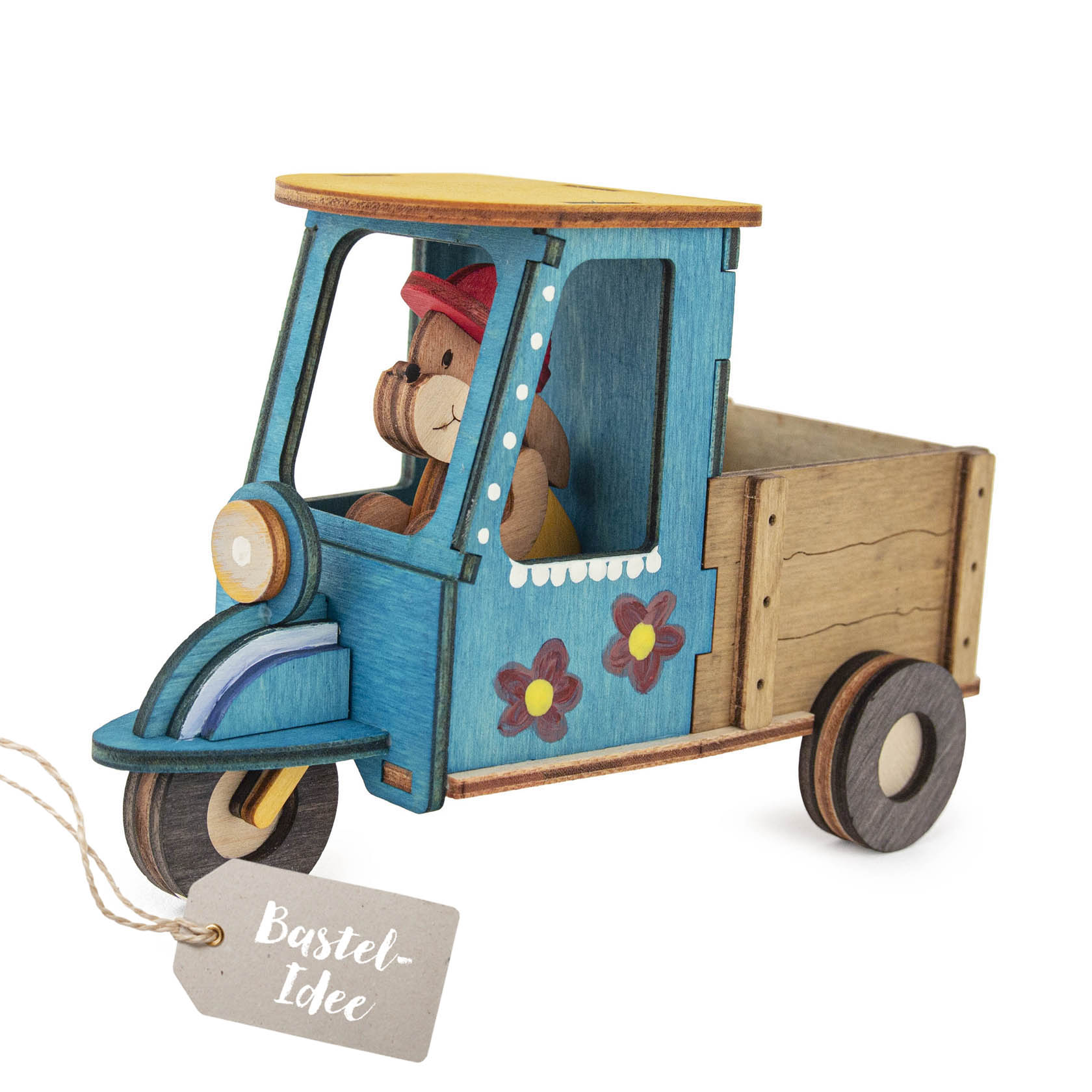 Ein Bastelset zeigt ein kleines, aus Holz zusammengebautes Fahrzeug mit drei Rädern, das einen Hasen als Fahrer in der Kabine und Blumen an der Seite hat. im Dregeno Online Shop günstig kaufen