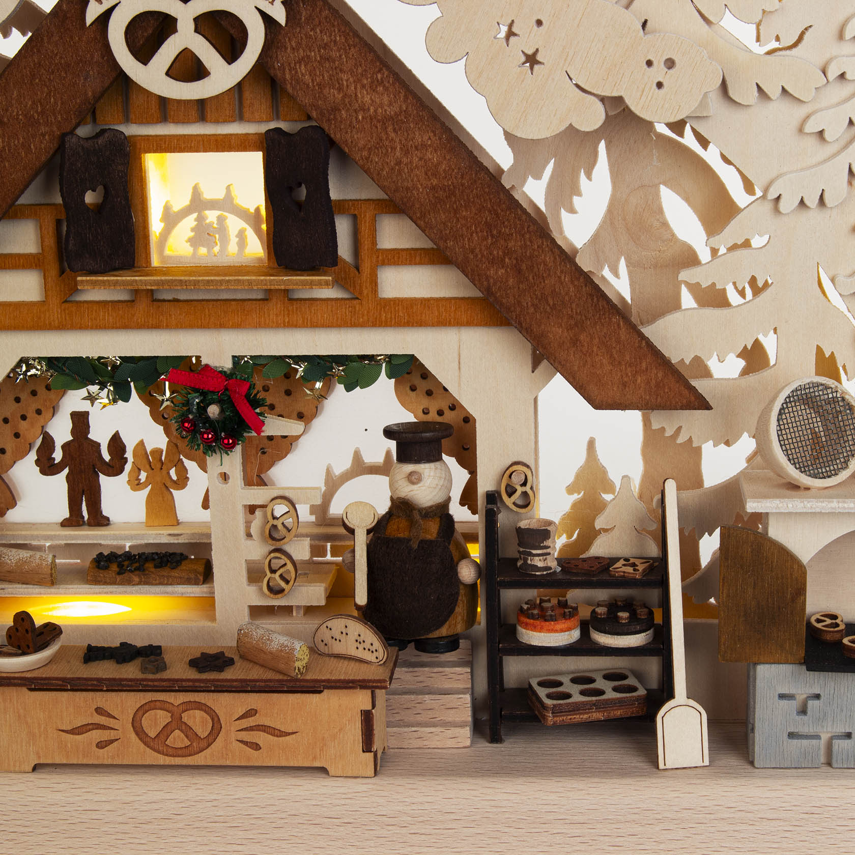A small, intricately designed wooden arch named 'Christmas Bakery', featuring indirect electric lighting and detailed figures of bakers and baked goods.