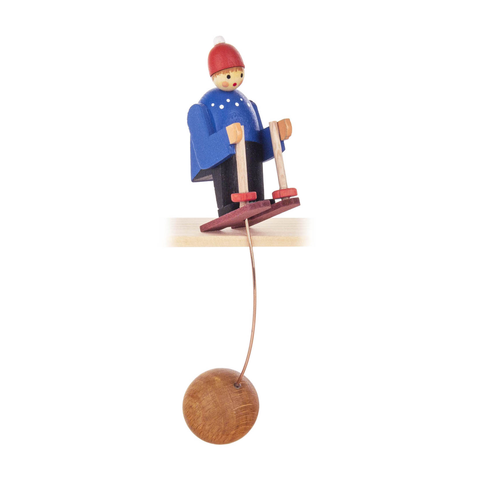 Holzfigur eines Skifahrers in blauem Mantel und roter Mütze, auf Skiern balancierend mit einer Holzkugel unten für Schaukelfunktion. im Dregeno Online Shop günstig kaufen