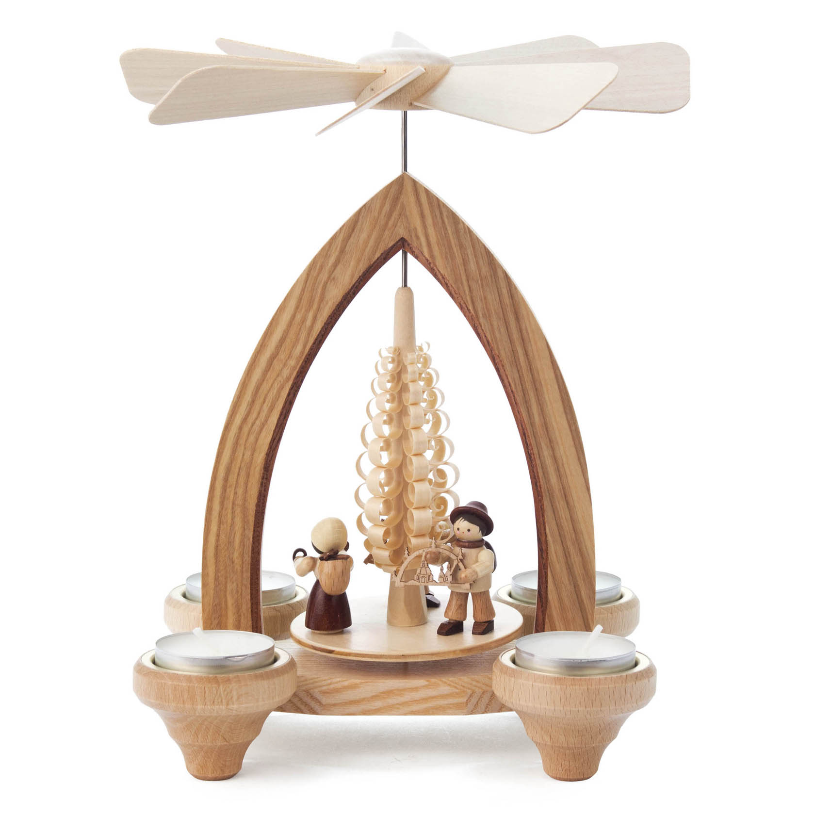 Holzpyramide mit drei Handelsfiguren und einem Baum in der Mitte, angetrieben durch Teelichtwärme, die ein helles Flügelrad dreht.