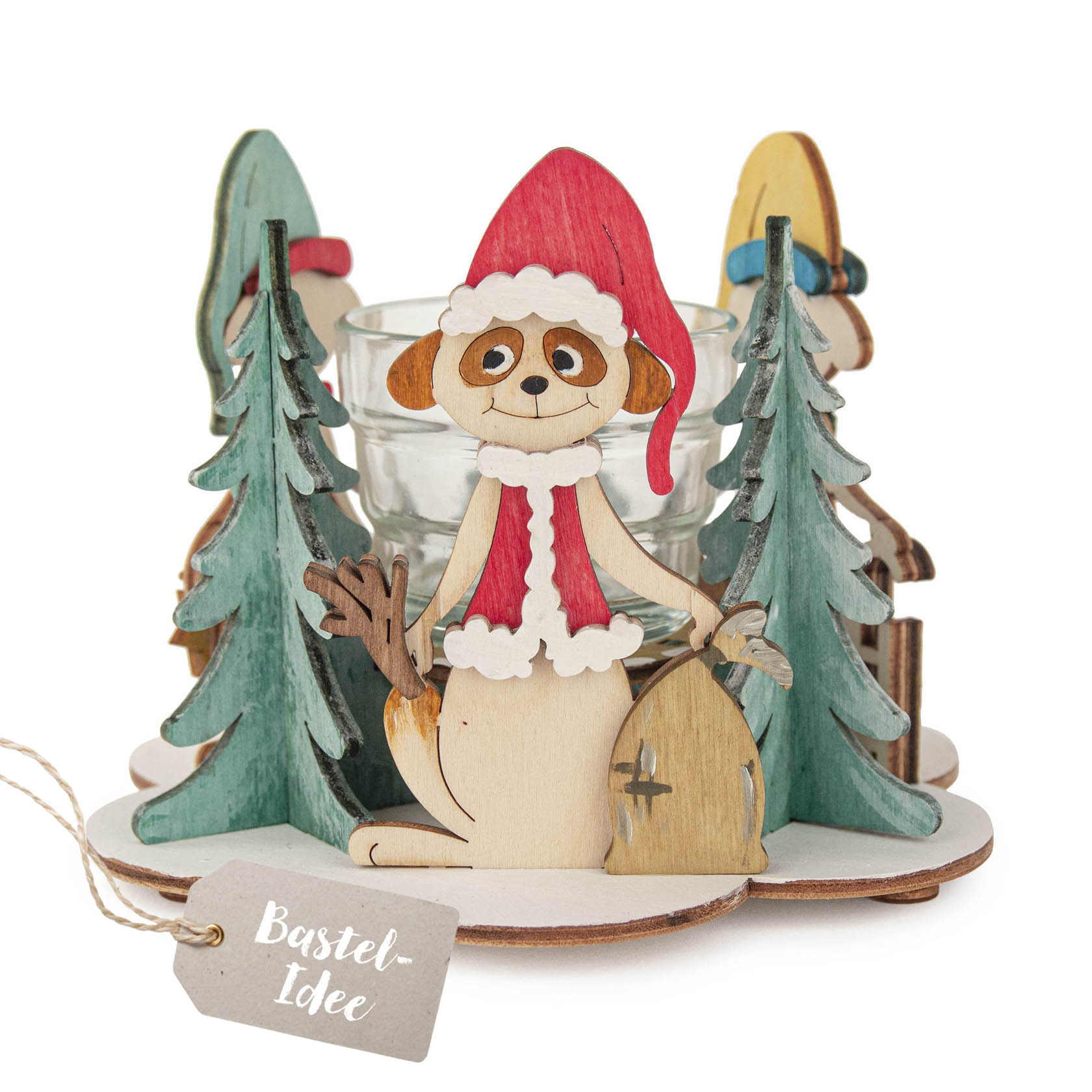 Ein Teelichthalter-Bastelset mit einem Erdmännchen in Weihnachtsmütze, umgeben von kleinen grünen Bäumen, die aus Holz gefertigt sind. im Dregeno Online Shop günstig kaufen