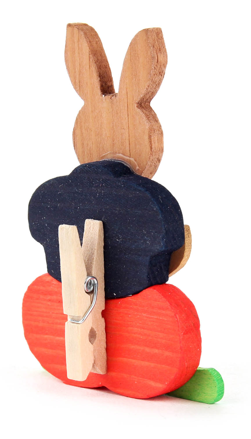 Holzosterhase mit blauen Hut und orangeroten Körper, nach hinten blickend. Eine Wäscheklammer ist an ihm befestigt.
