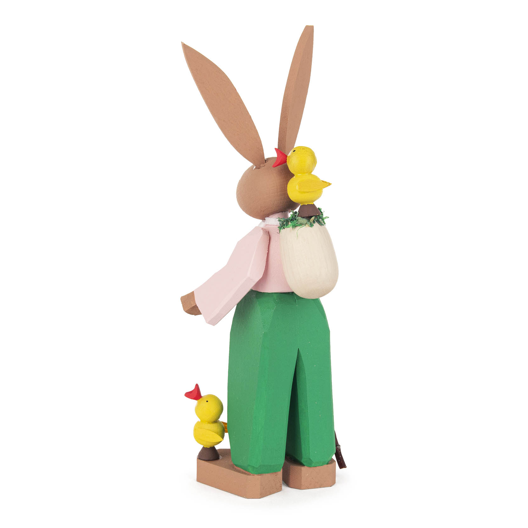 Holzfigur des Osterhasen Hugo mit braunen langen Ohren, rosa Hemd, grüner Hose. Trägt einen weißen Rucksack, gelbe Küken sitzen auf Kopf und Schulter.