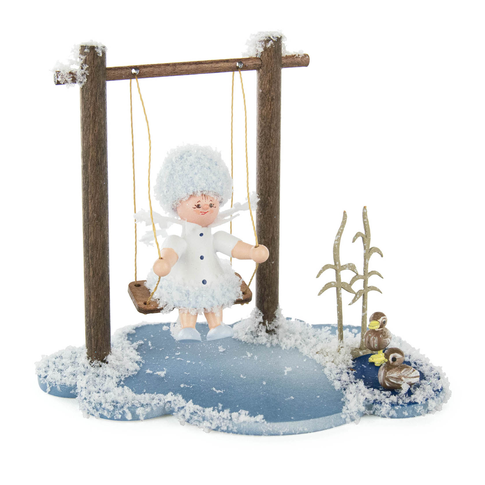 Dekorationsfigur Schneeflöckchen als Engel auf einer Holzschaukel, umgeben von künstlichem Schnee und Pflanzendekoration. im Dregeno Online Shop günstig kaufen