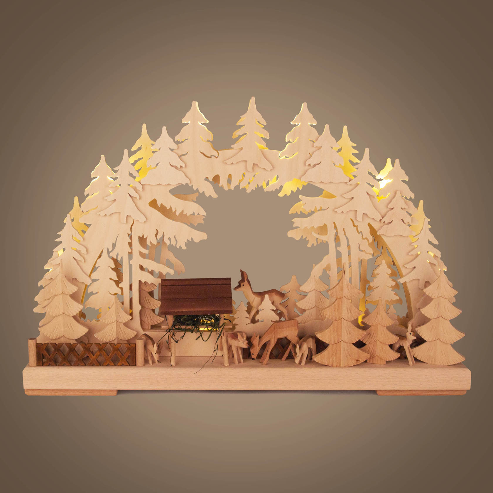 Ein kleiner Schwibbogen aus Holz mit indirekter Beleuchtung, zeigt eine Wildfütterungsszene mit Rehen im Wald.