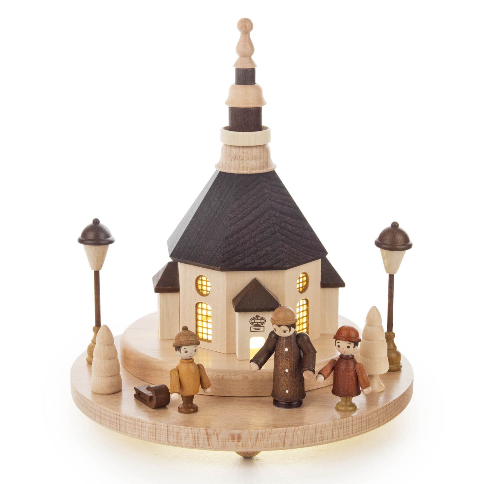 Holzmodell einer Kirche mit dunklem Dach und LED-Beleuchtung, umgeben von drei Holzfiguren und zwei Laternen auf einem runden Sockel.