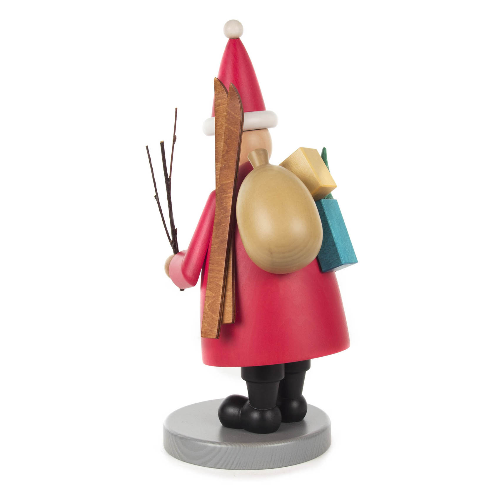 Ein hölzerner Räuchermann in Form eines Weihnachtsmannes mit rotem Mantel, braunem Rucksack, Skiern und Geschenken auf dem Rücken, steht auf einem Sockel.