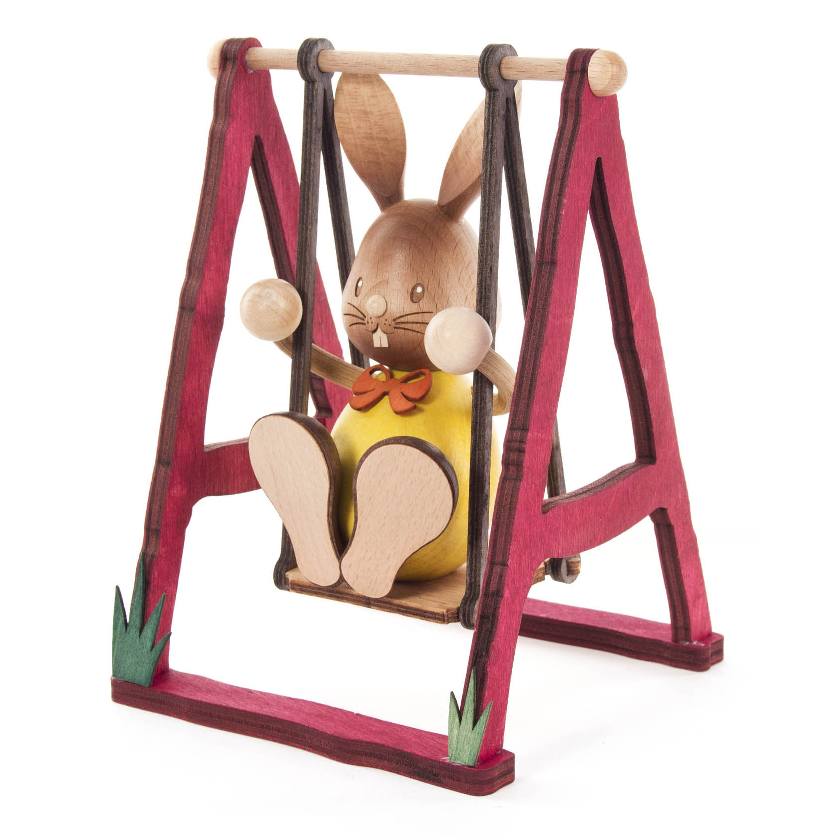 Holzfigur eines sitzenden Hasen namens 'Stupsi' auf einer roten Holzschaukel mit gelbem Körper und Schleife um den Hals.