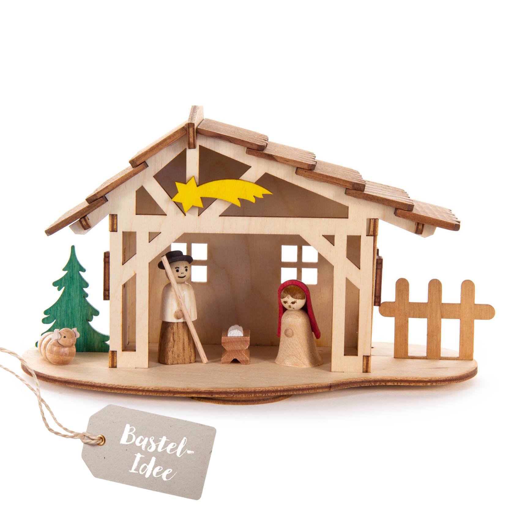 Ein Miniatur-Krippenstall aus Holz mit Figuren von Maria, Josef, dem Jesuskind und einem Schäfchen, neben einem grünen Baum und einem Holzzaun. im Dregeno Online Shop günstig kaufen