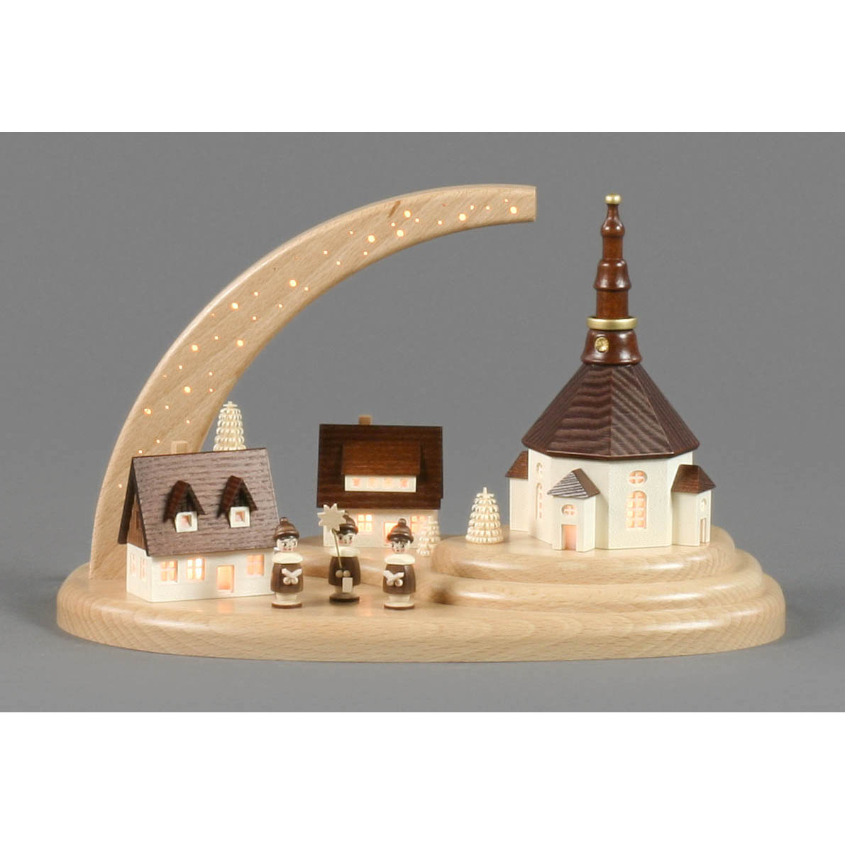Holzmodell eines Dorfes mit zentraler Kirche und drei Kurrendesängern auf einem Sockel, beleuchtet durch einen gebogenen Sternenhimmel mit elektrischer Beleuchtung.
