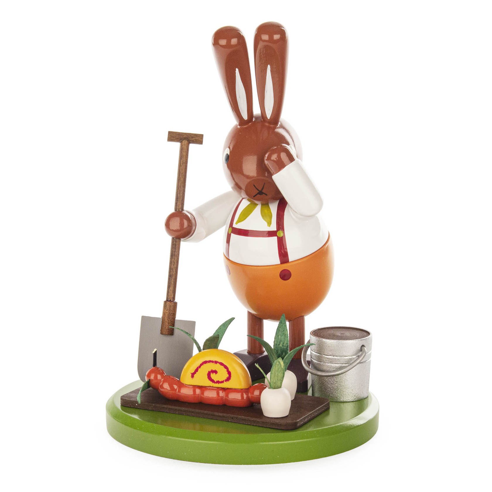 Holzfigur eines Hasen mit Schaufel, neben einer Schnecke und einer Rübe. Der Hase trägt eine Schürze und steht auf einem grünen Sockel.