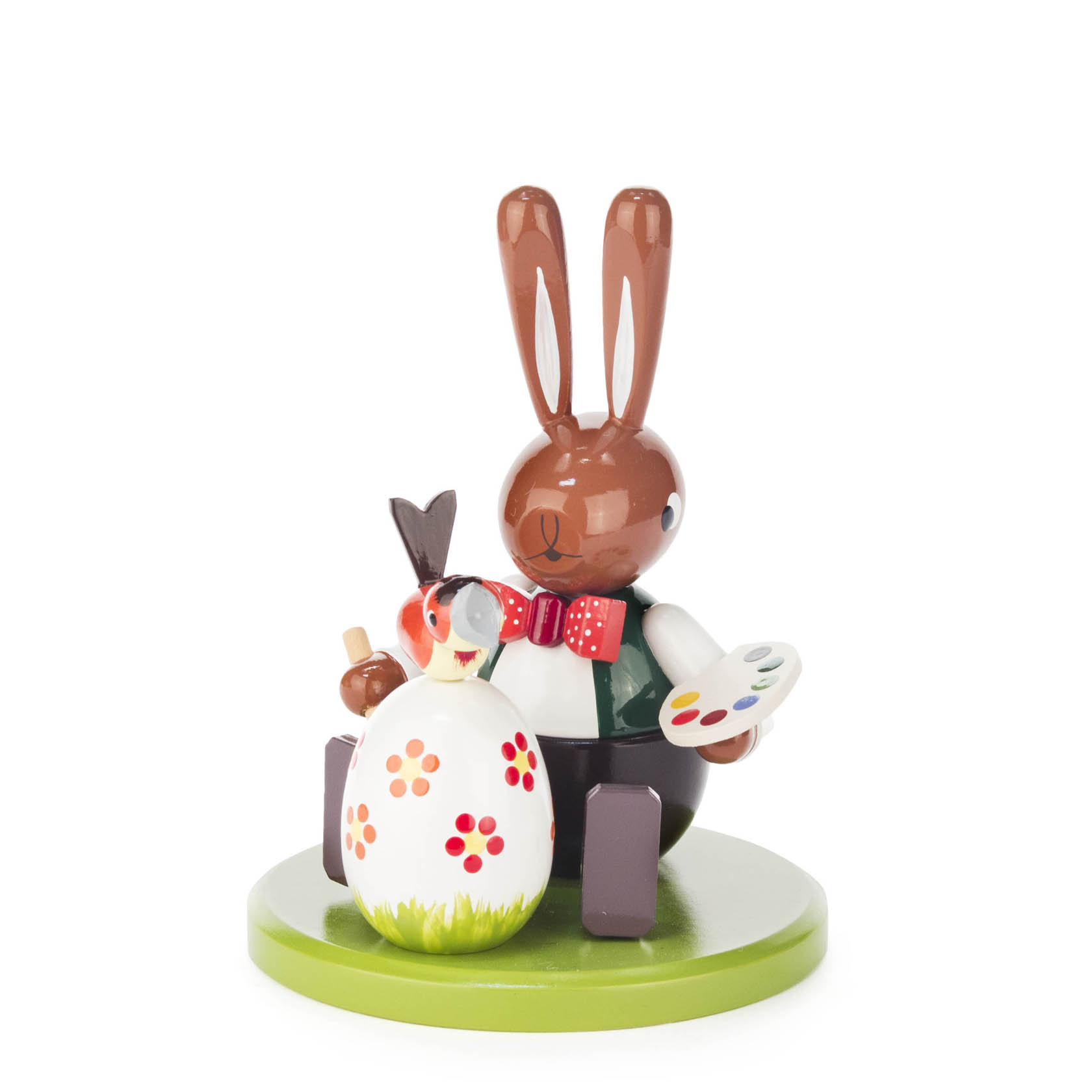 Sitzende Hasenfigur mit Pinsel und Farbteller bemalt ein großes Osterei mit roten und gelben Blumen. im Dregeno Online Shop günstig kaufen