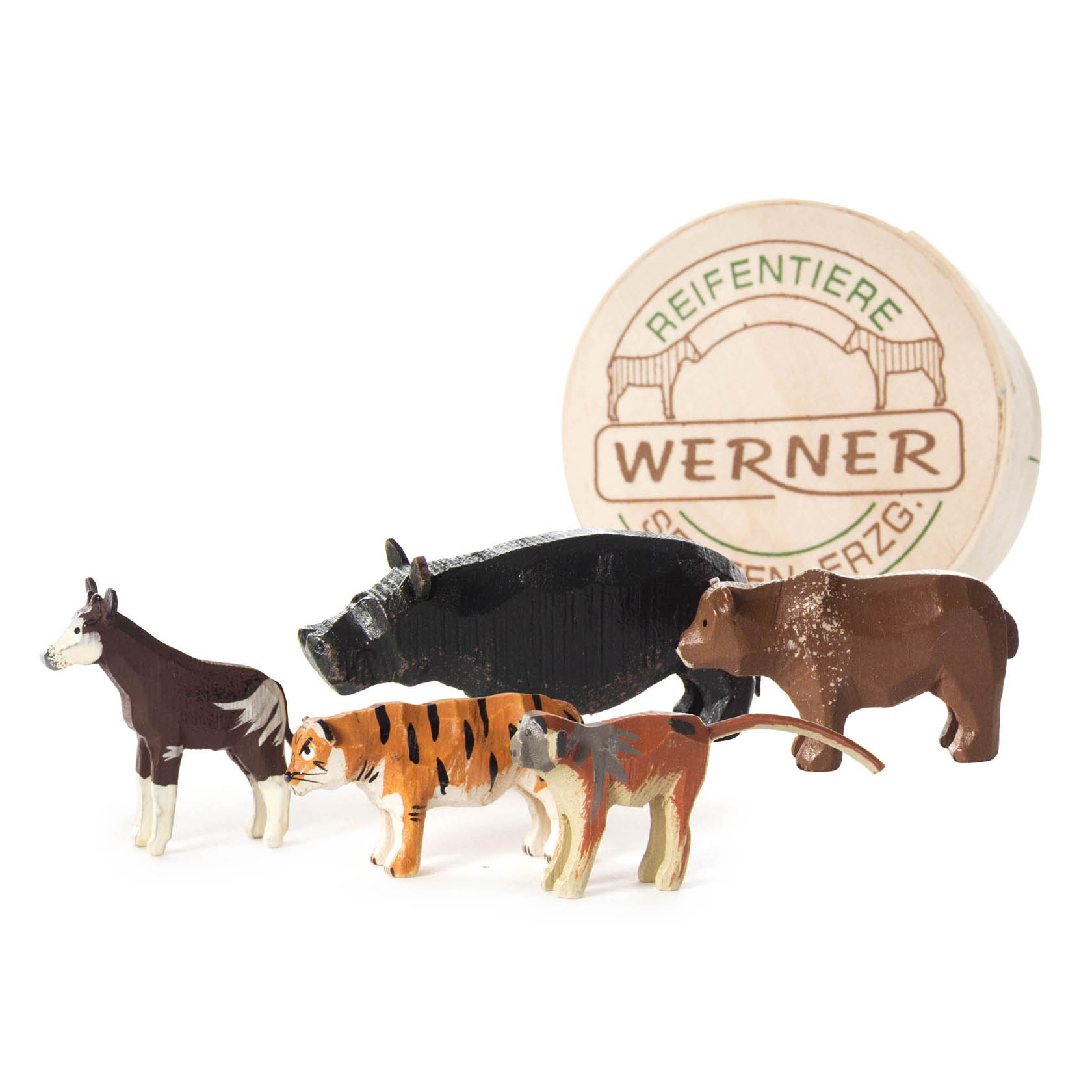Vier handgeschnitzte Holztierfiguren, darunter Esel, Wildschwein, Tiger und ein Fuchs, stehen vor einer runden Holzverpackung mit der Aufschrift 'Werner'. im Dregeno Online Shop günstig kaufen