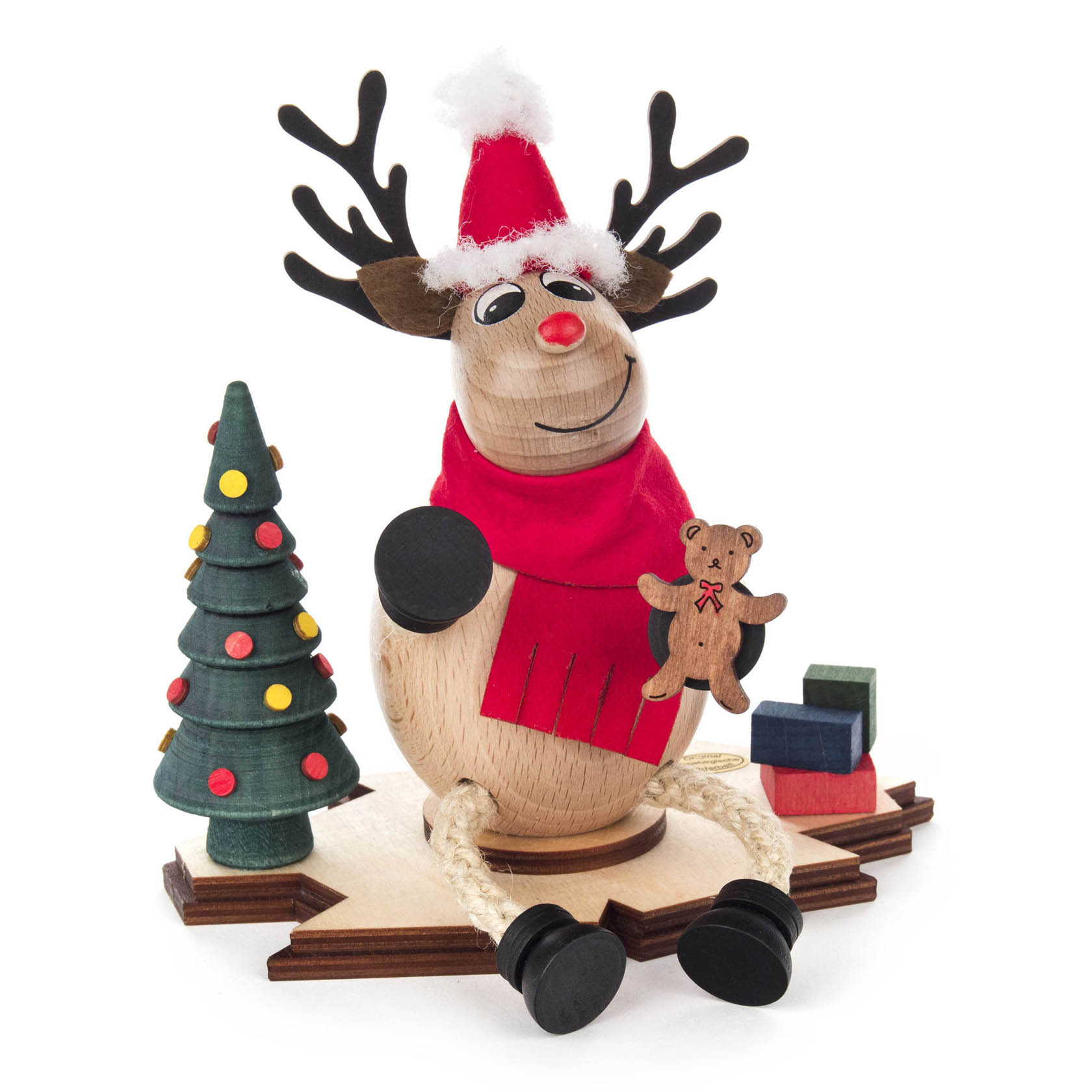 Holzfigur eines fröhlichen Elchs mit Weihnachtsmann-Mütze, rotem Schal und Mantel. Der Elch hält einen kleinen Teddybär in der Hand, neben ihm ein geschmückter Baum. im Dregeno Online Shop günstig kaufen