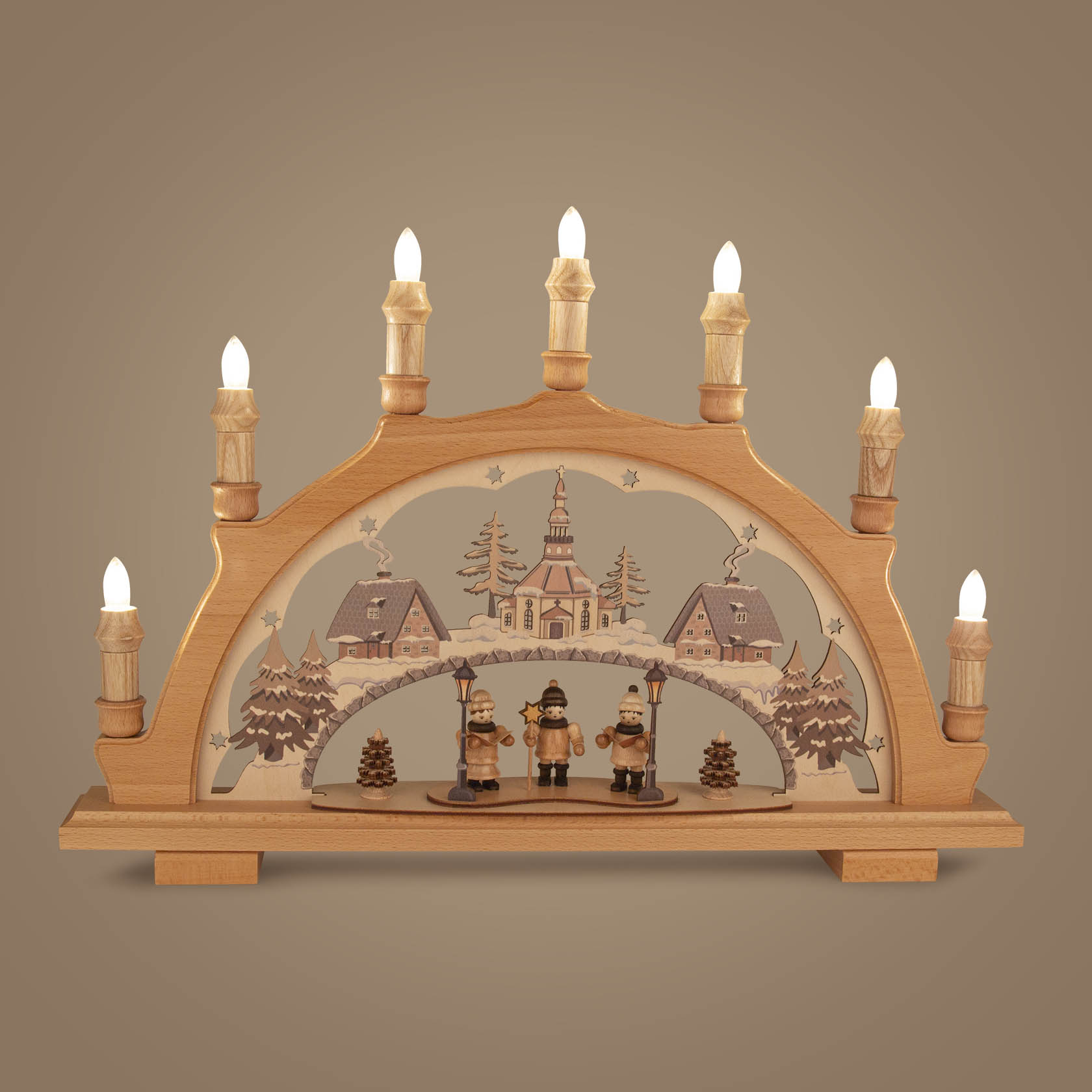 Schwibbogen mit LED Beleuchtung, zeigt drei Sternensänger im Vordergrund vor einer Winterlandschaft mit Kirche und Häusern.