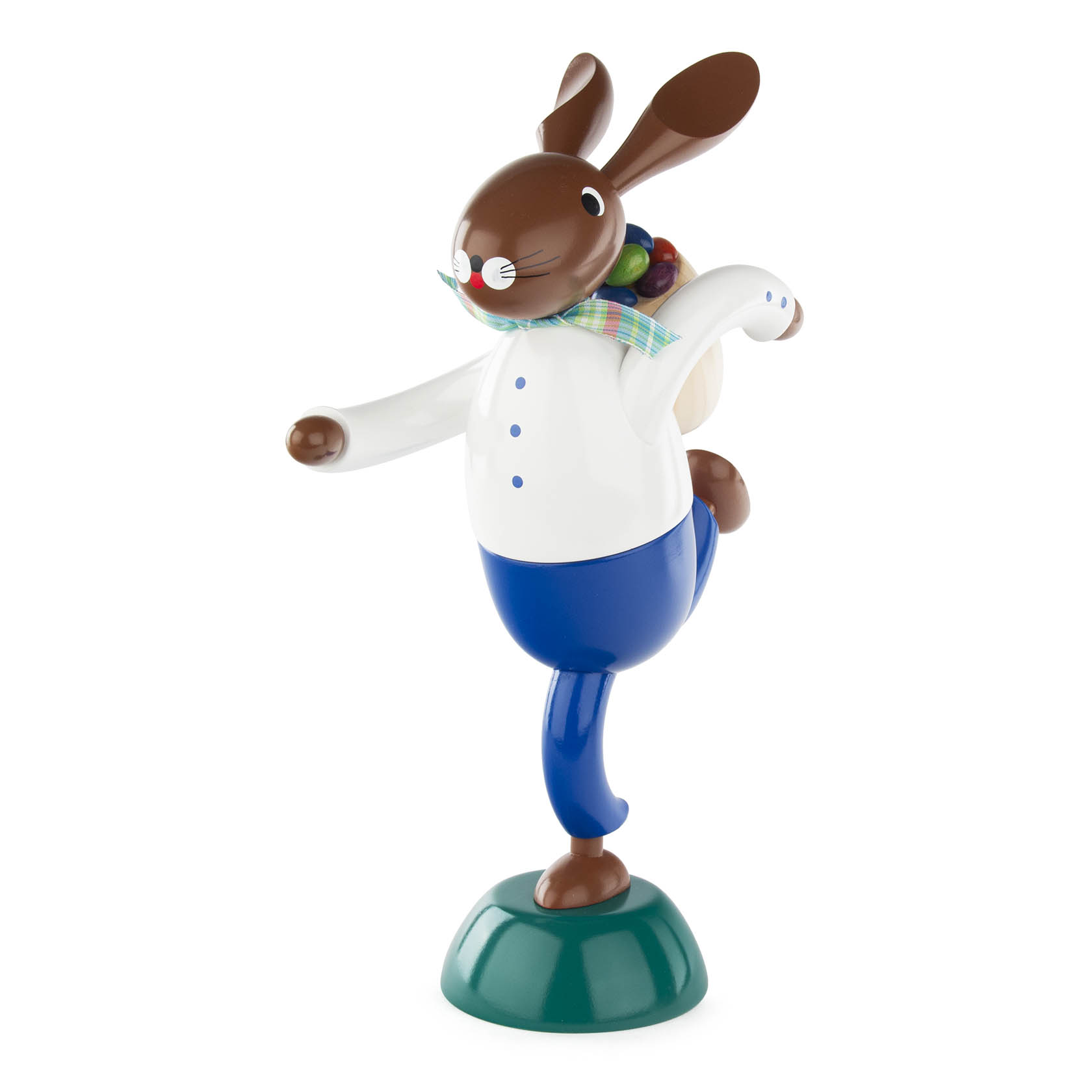 Holzfigur eines Hasen in blauer Hose, weißen Hemd und bunter Krawatte, balancierend auf einem Bein mit bunter Kiepe auf dem Rücken.
