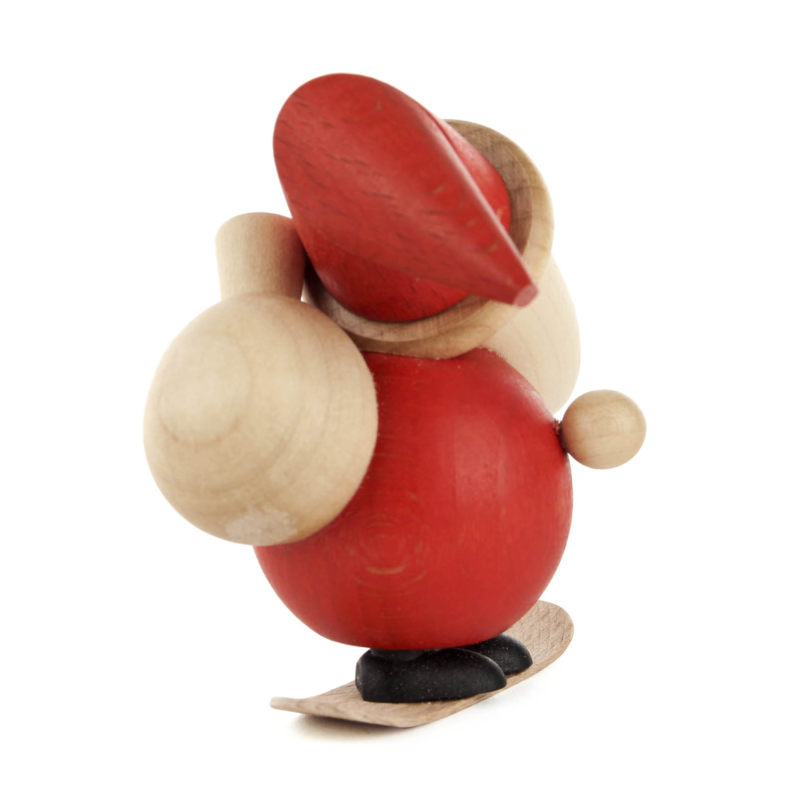 Eine kleine Holzfigur des Weihnachtsmanns, der auf einem Snowboard steht, mit rotem Mantel und Mütze, mit weißem Bart und einem Sack auf dem Rücken.