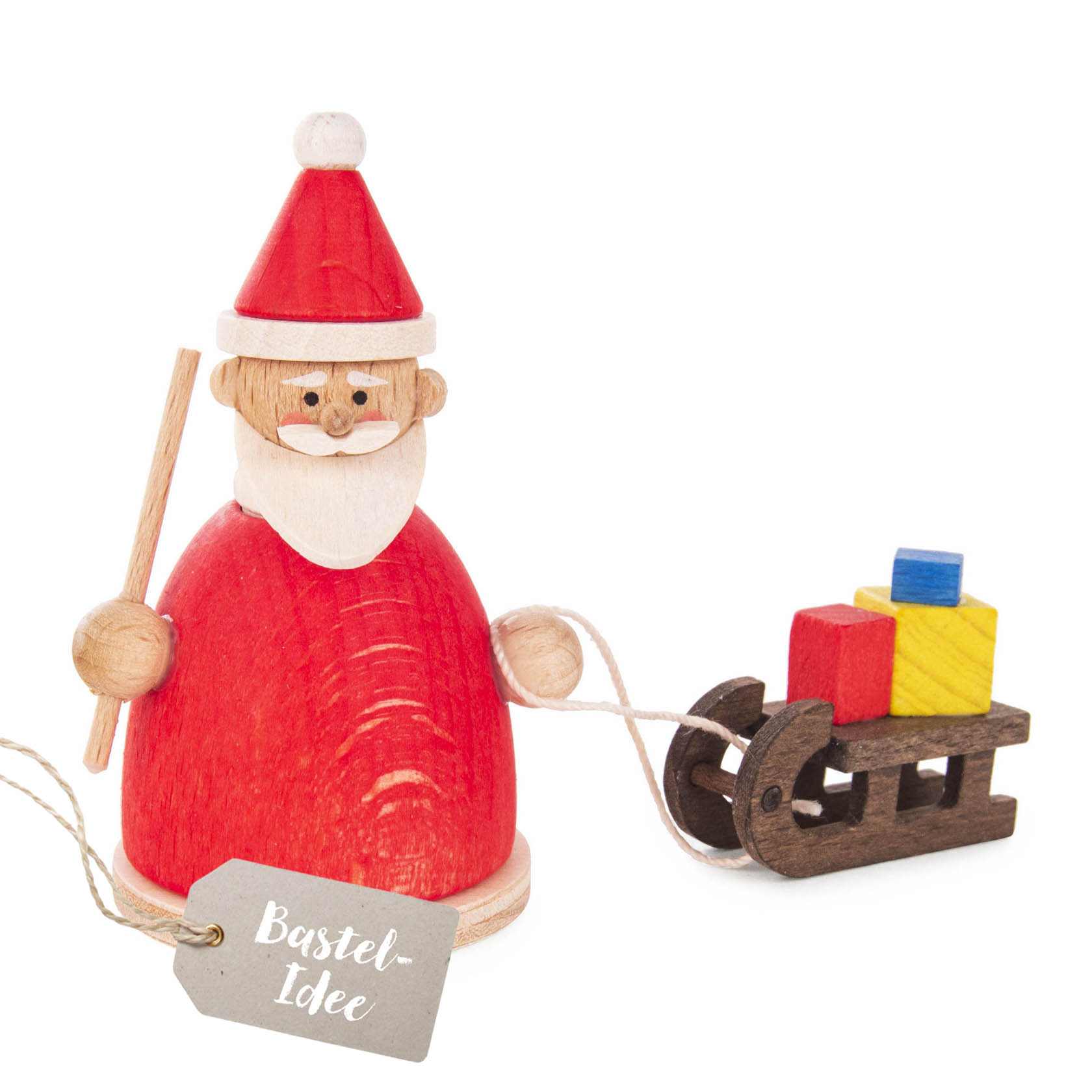Bastelset mit einem lachenden Weihnachtsmann in rotem Mantel und Mütze, hält einen Stock und zieht einen kleinen Schlitten mit bunten Geschenken. im Dregeno Online Shop günstig kaufen