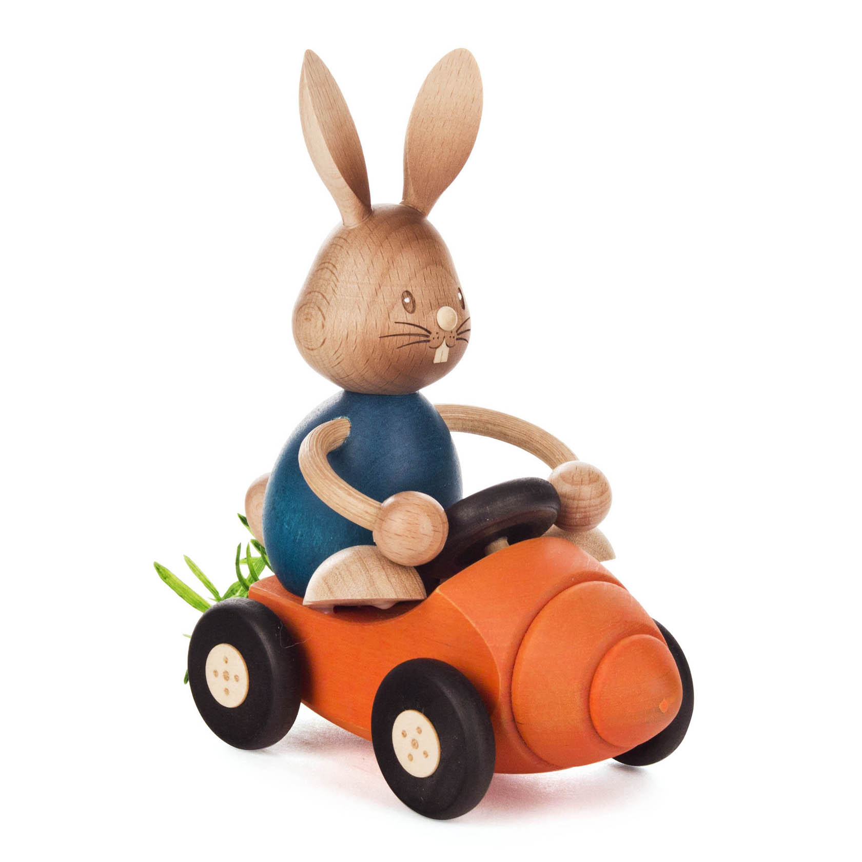 Holzhase 'Stupsi' sitzt in einem Möhrenflitzer mit vier Rädern und einem Lenkrad. Der Flitzer ist orange und hinten schauen Möhrenblätter heraus. im Dregeno Online Shop günstig kaufen
