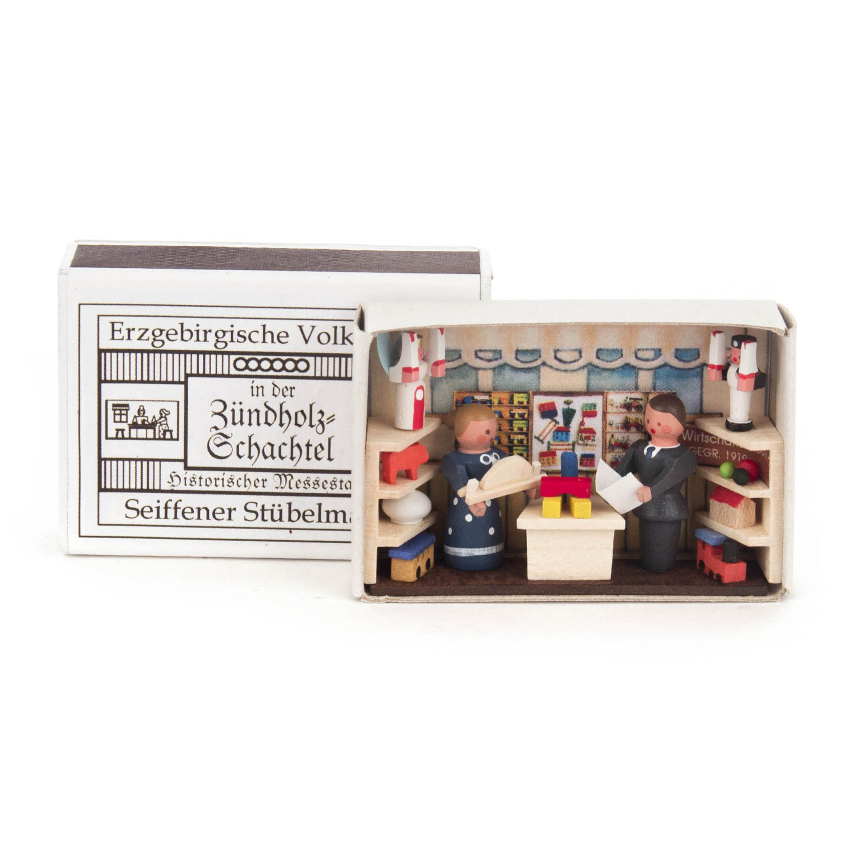 Detailreiche Miniatur-Darstellung eines Messestands in einer Zündholzschachtel, zwei Holzfiguren symbolisieren Händler, mit Deko-Elementen und Produkten. im Dregeno Online Shop günstig kaufen