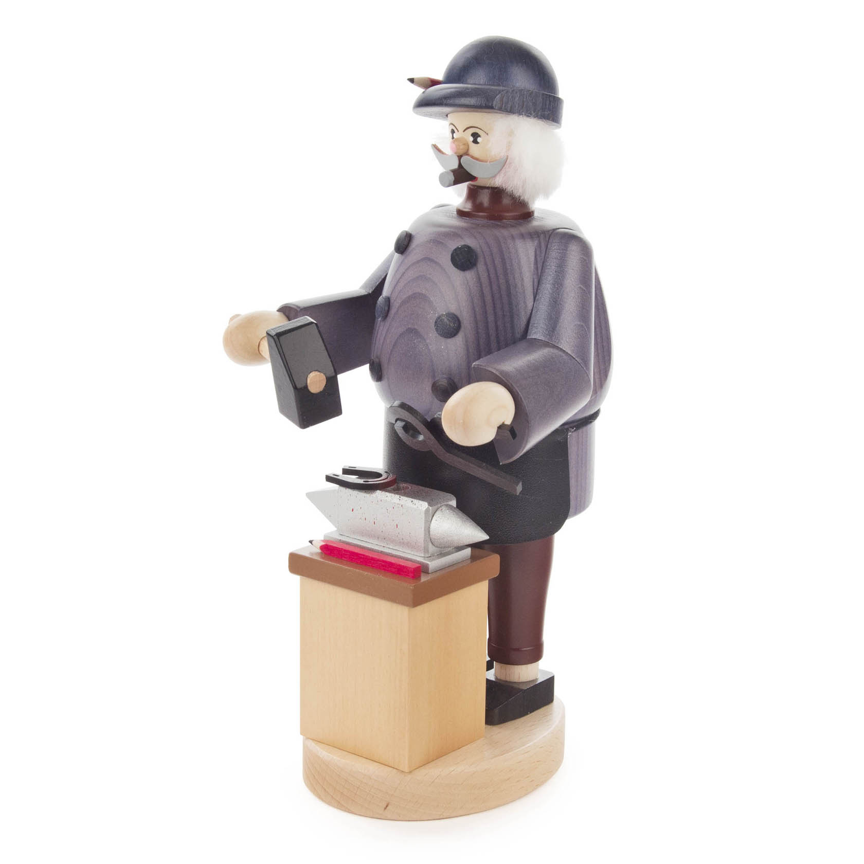 Holzfigur eines Schmieds mit Bart und Mütze, der an einem Amboss arbeitet. Der Schmied trägt eine Schürze und hält einen Hammer in seiner Hand.