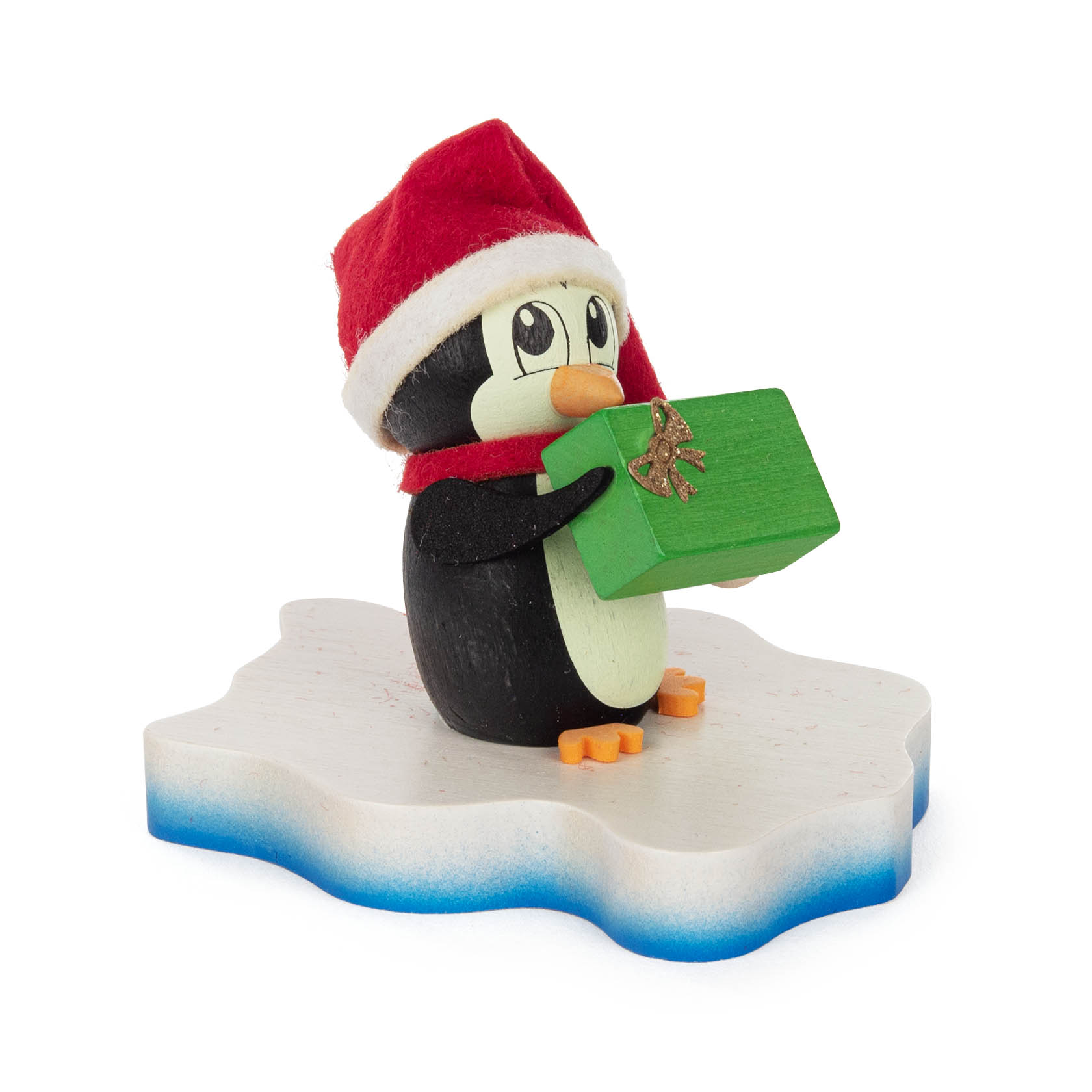 Ein kleiner Pinguin mit roter Weihnachtsmütze hält ein grünes Geschenk in den Flossen, stehend auf einer weißen, eisförmigen Basis. im Dregeno Online Shop günstig kaufen