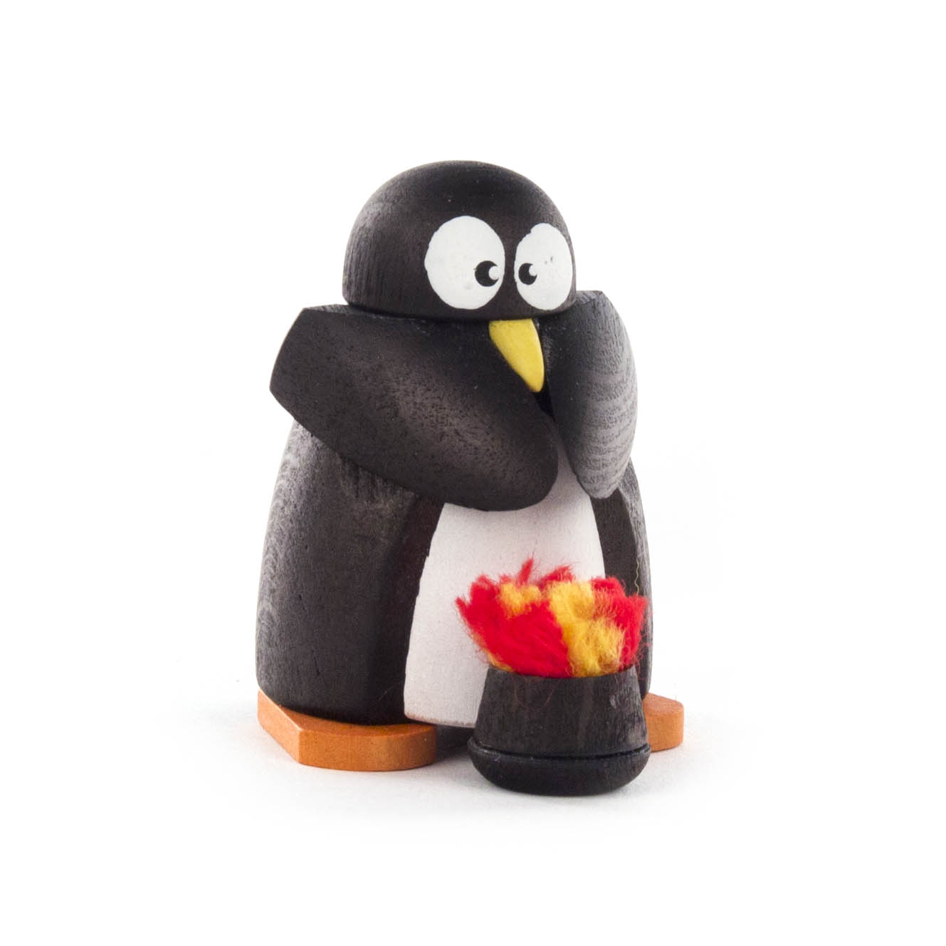 Holzfigur eines Pinguins, der seine Flossen an einem kleinen Feuer wärmt. Der Pinguin hat große Augen und steht auf orangefarbenen Füßen. im Dregeno Online Shop günstig kaufen