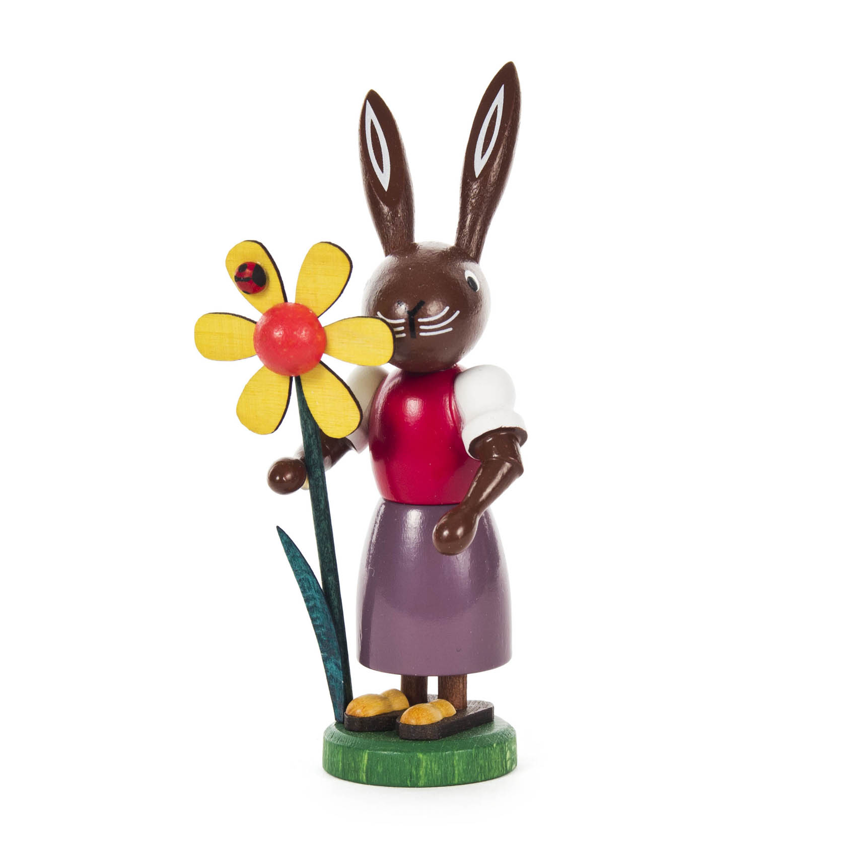 Eine Holzfigur einer braunen Häsin mit roten Kleid und lila Rock, die eine große gelbe Blume mit rotem Zentrum und einem Marienkäfer hält. im Dregeno Online Shop günstig kaufen