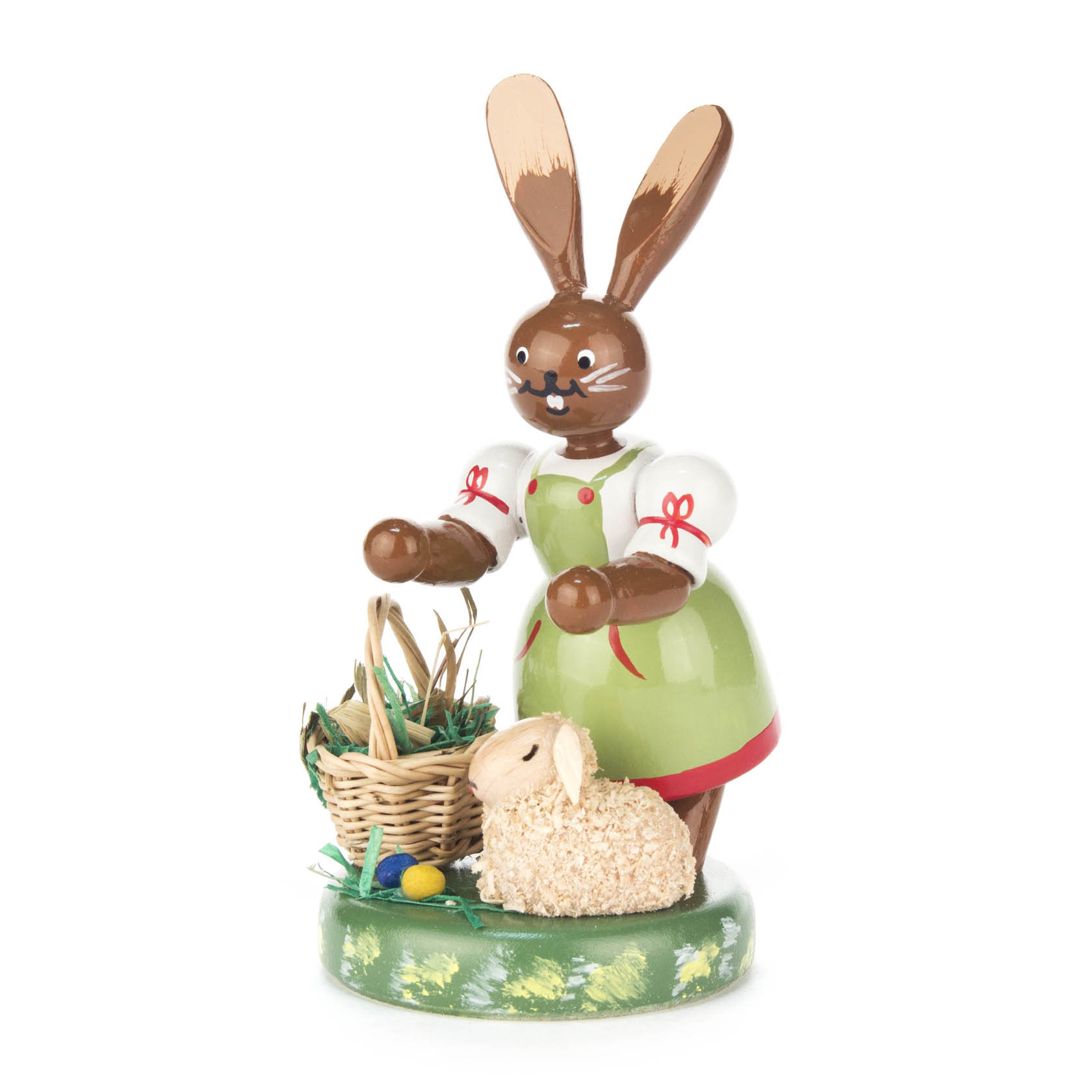 Holzfigur einer Häsin mit grüner Schürze und weißen Ärmeln, neben einem Schaf und einem Korb mit Gras und Ostereiern. im Dregeno Online Shop günstig kaufen